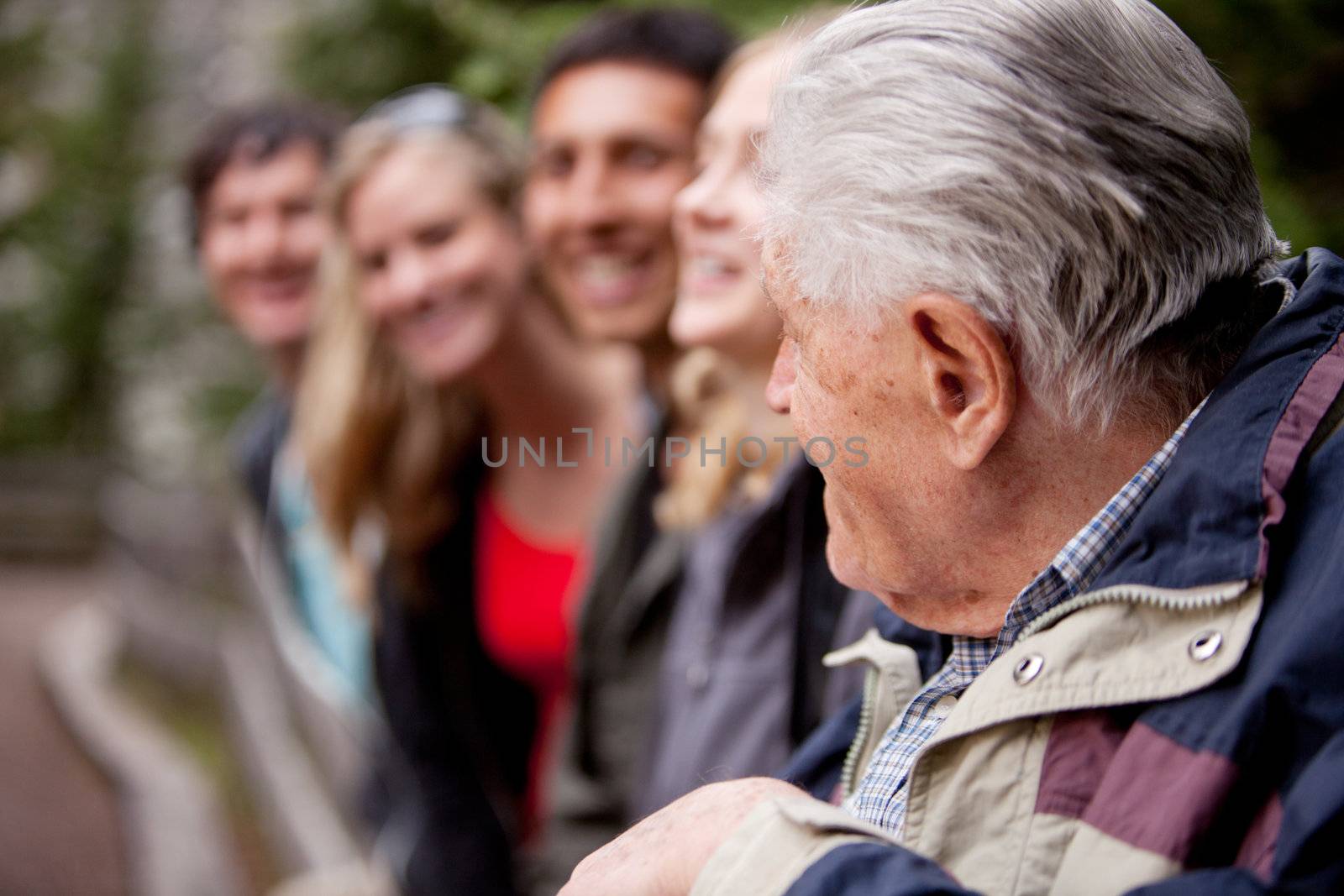 An elderly man guiding a group of young people in the forest