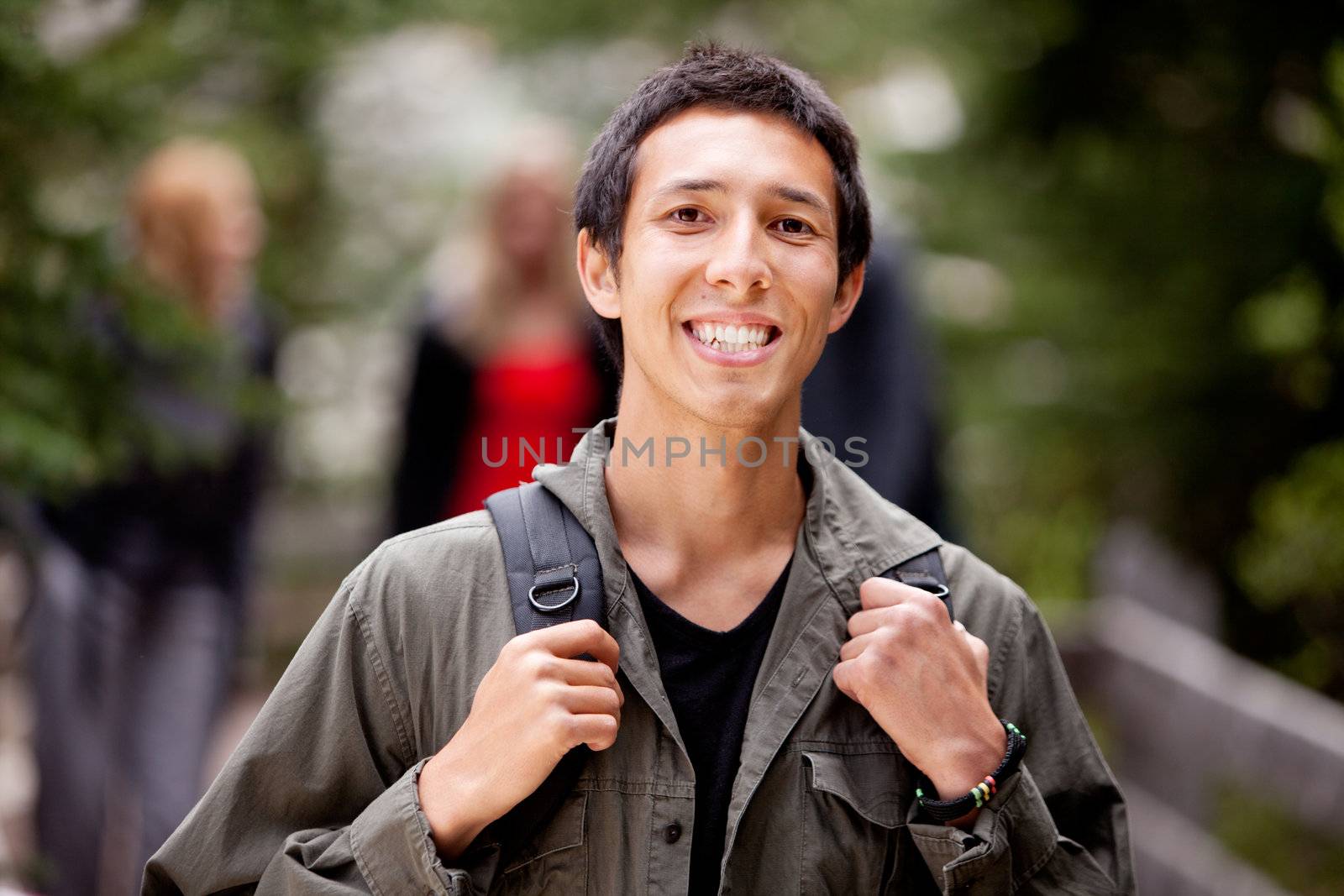 A happy camper smiling at the camera with a backpack outdoors