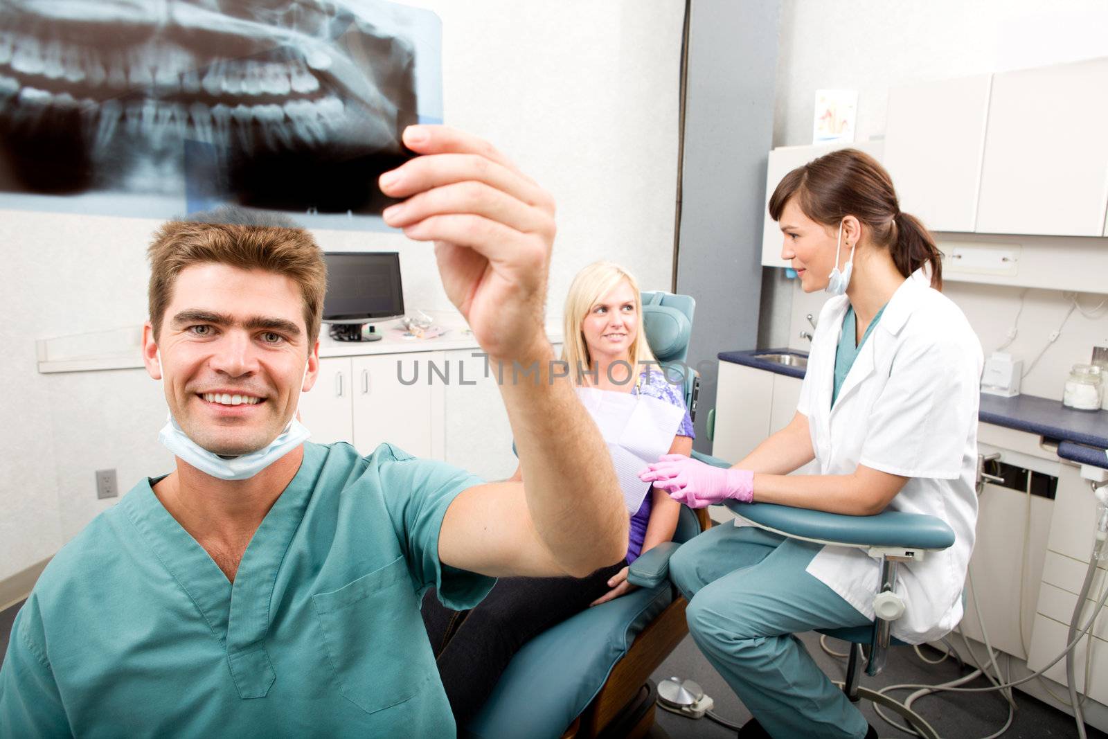 A dentist holding an x-ray while looking and smiling at the camera