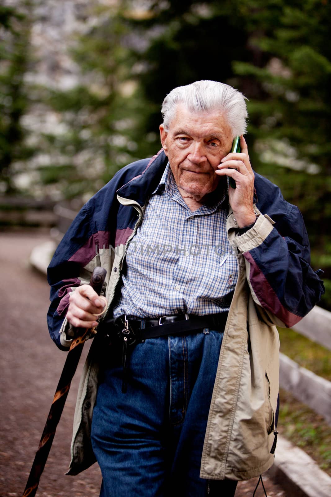 A senior talking on a cell phone outdoors in the forest