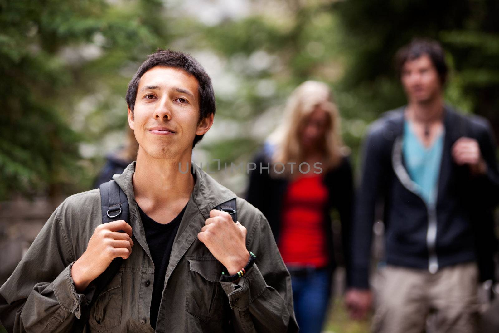 A man backpack camping in the forest with a group of friends in the background