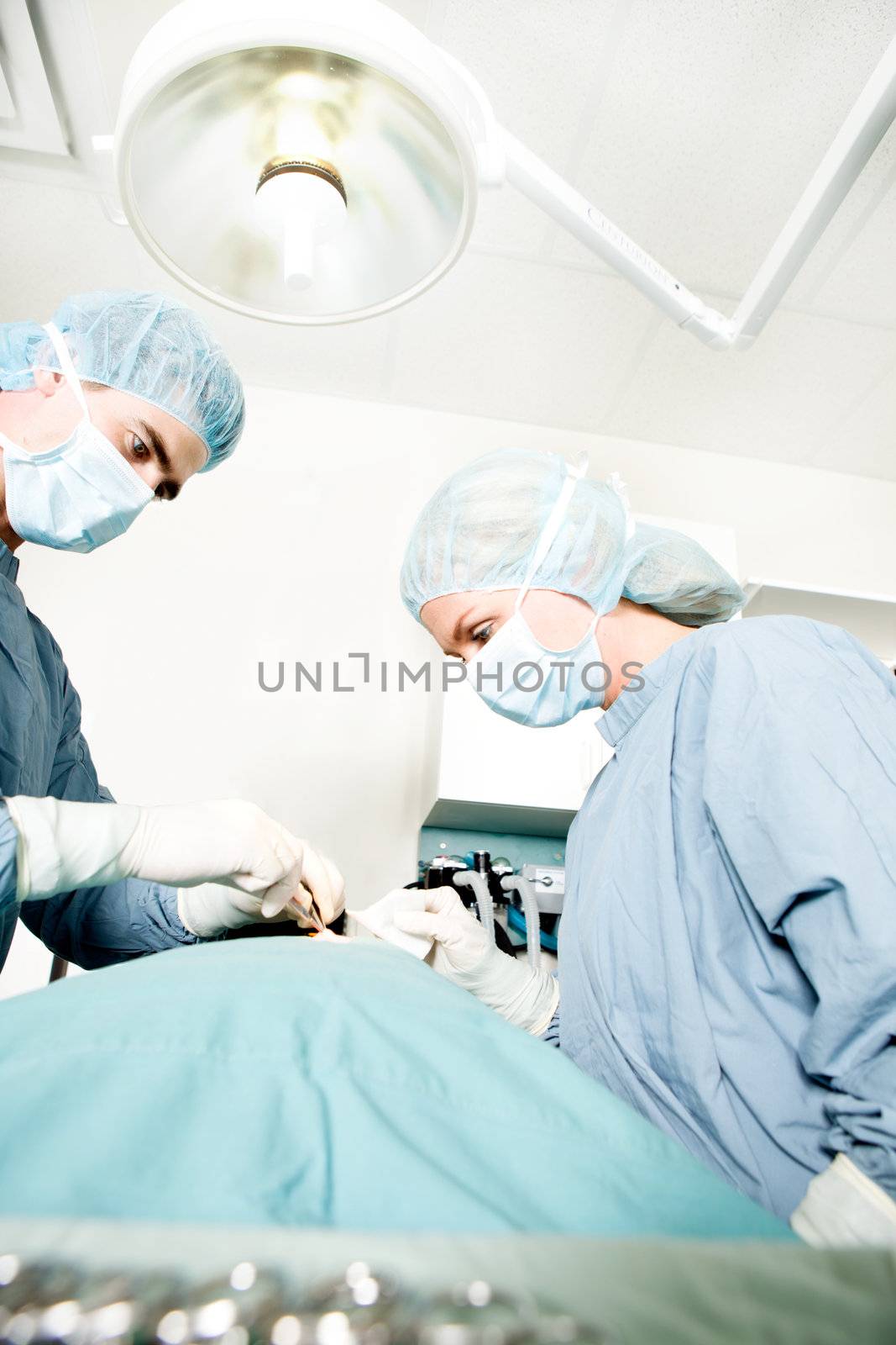 A surgeon working in a small operating room with an assistant