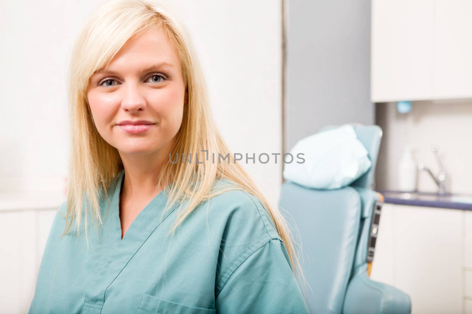 A portrait of a dental hygienist in front of a dental chair