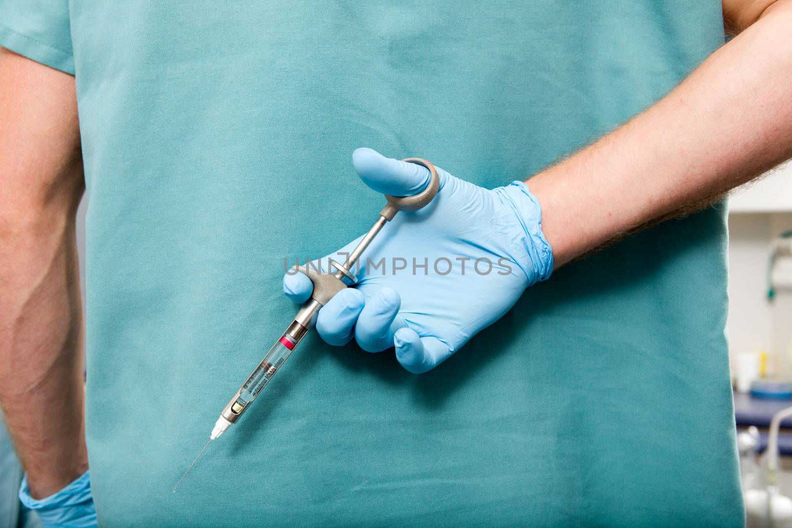 A large needle behind the back of a dentist