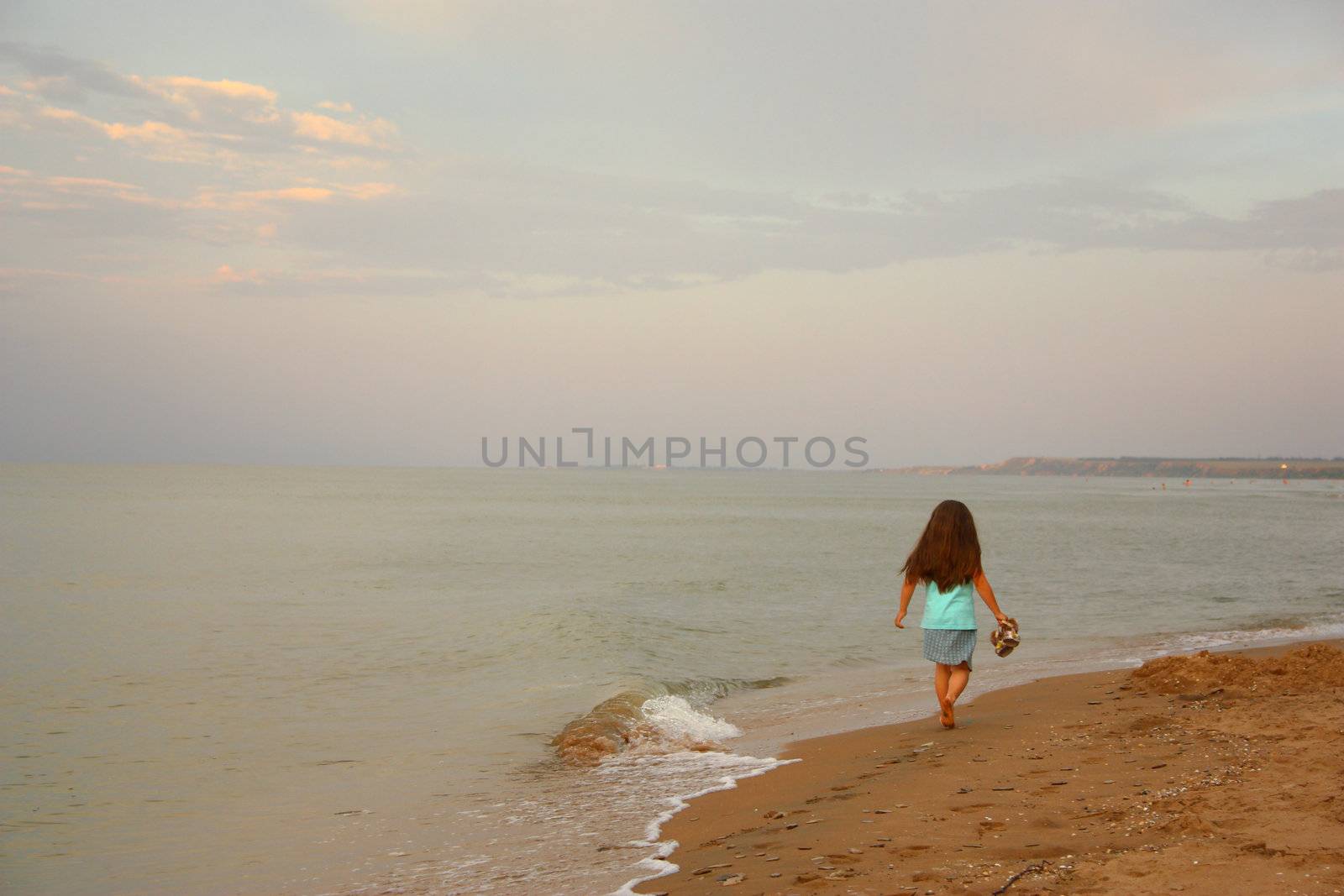 Little girl walks barefoot on seacoast