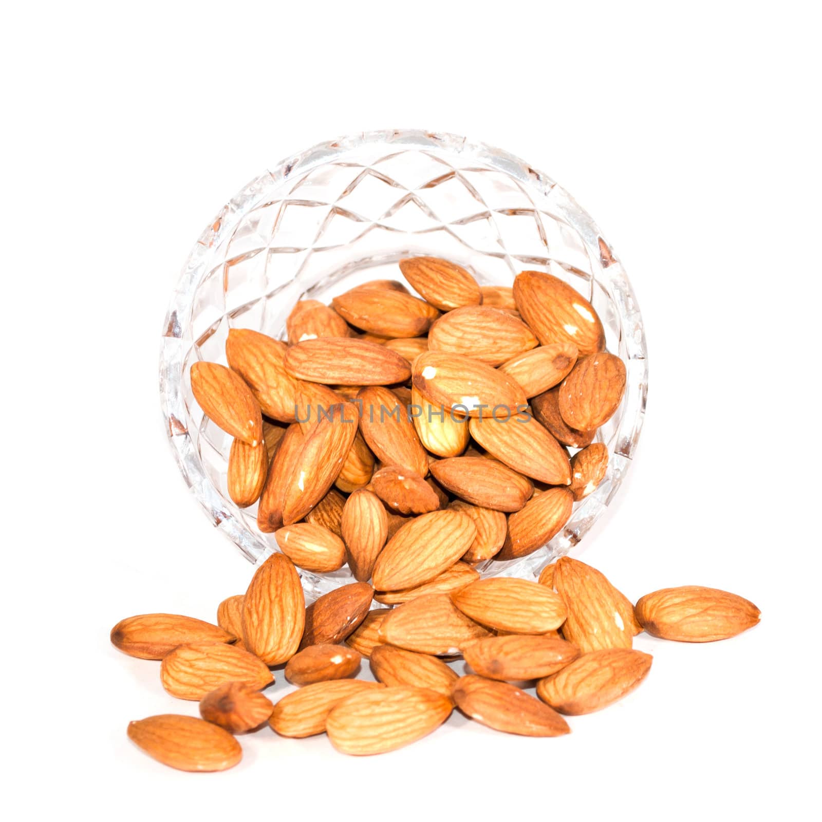 A glass bowl of almonds isolated on white