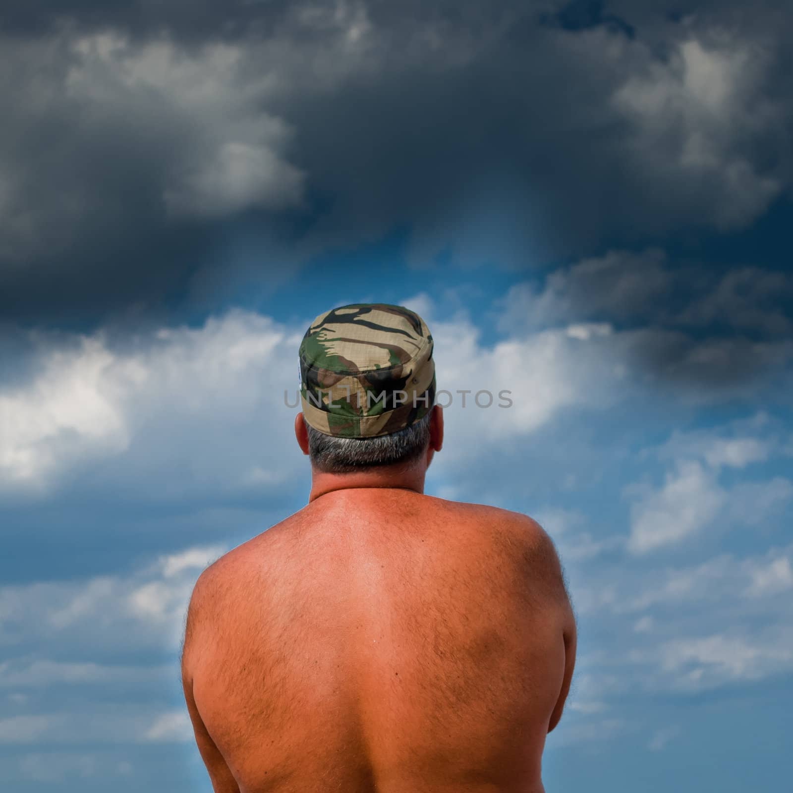 Shirtless army man waiting for the storm to come.