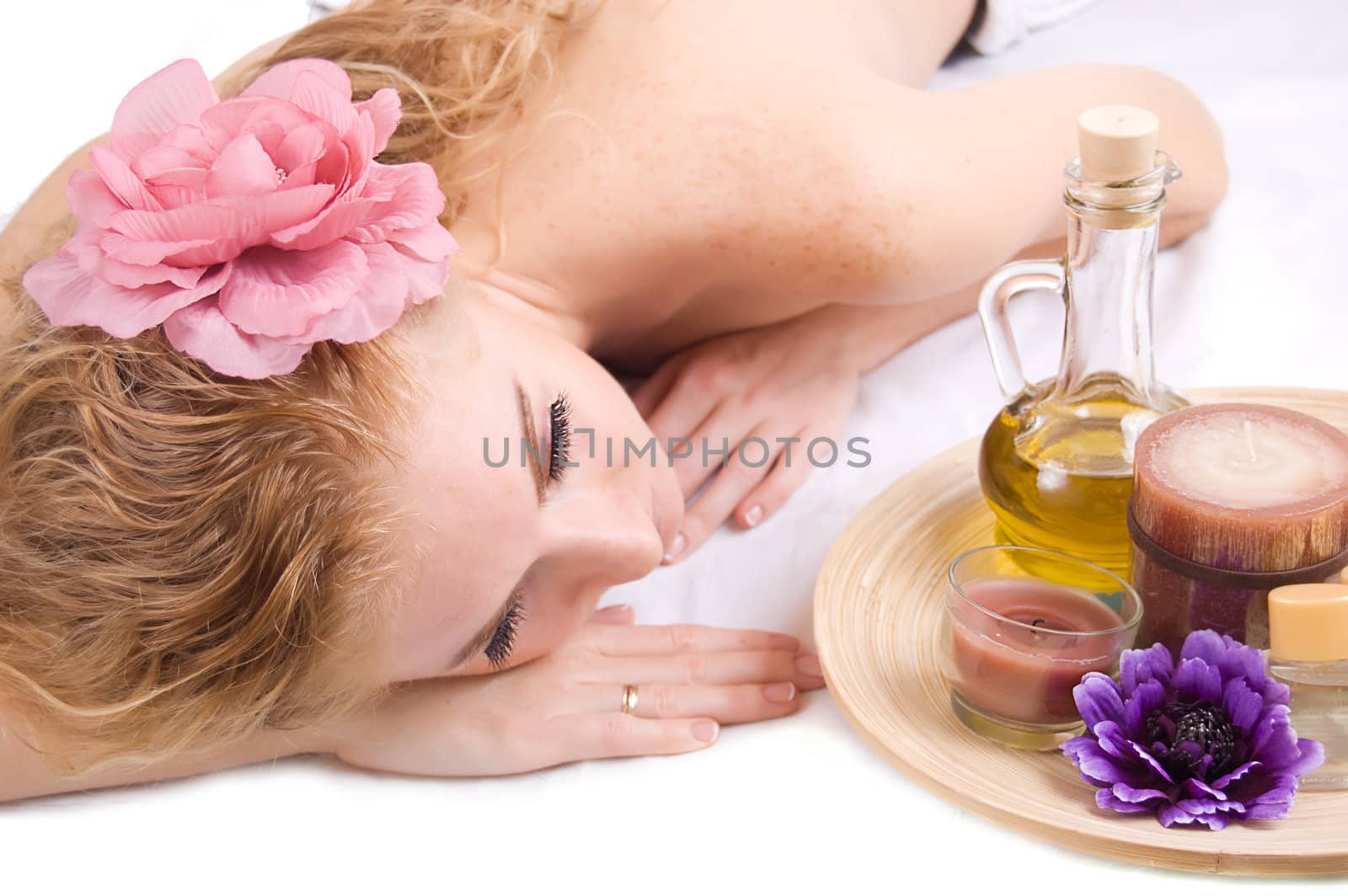 Redheaded woman lying with spa products over white