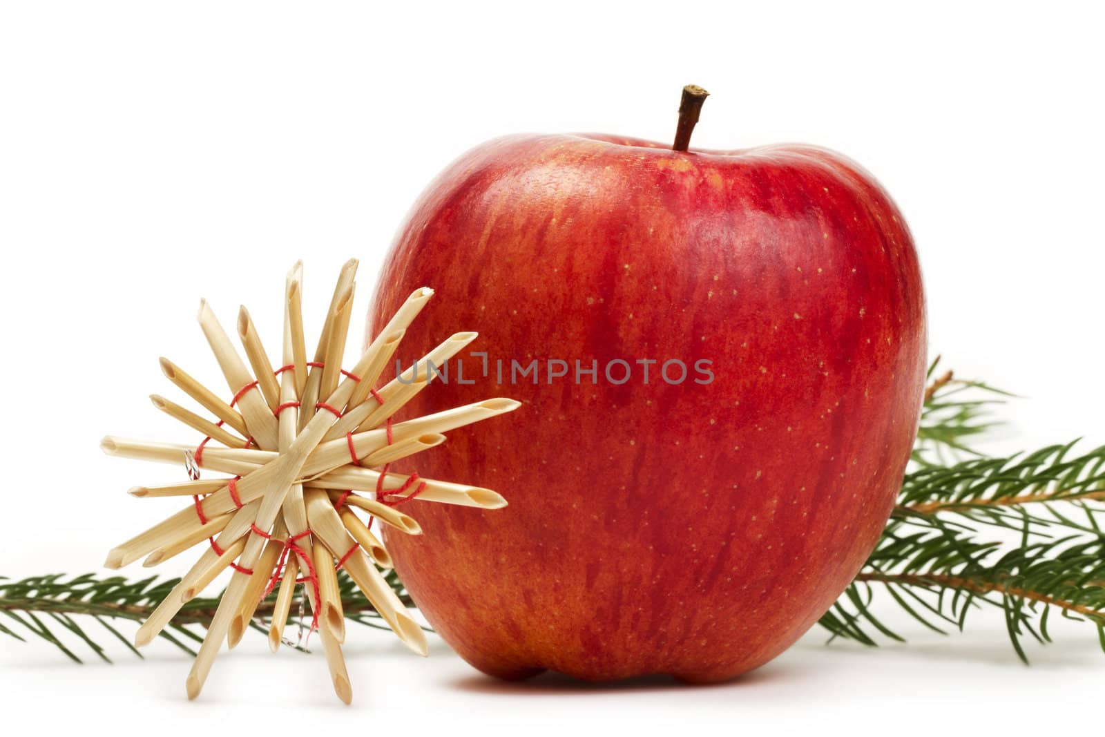 red apple with a straw star in front of a branch on white background