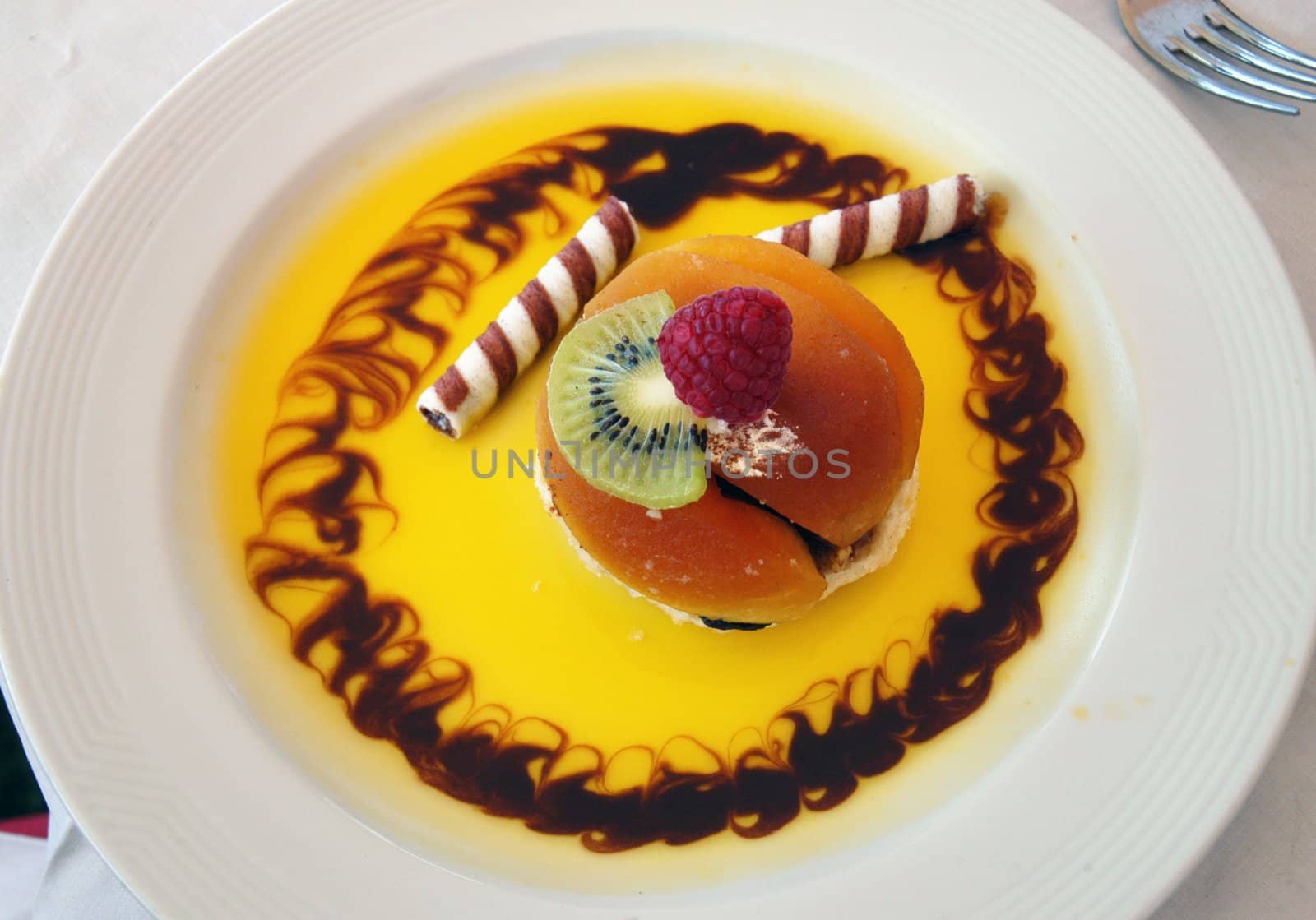 Sweet fruit dessert with yellow sauce on white plate