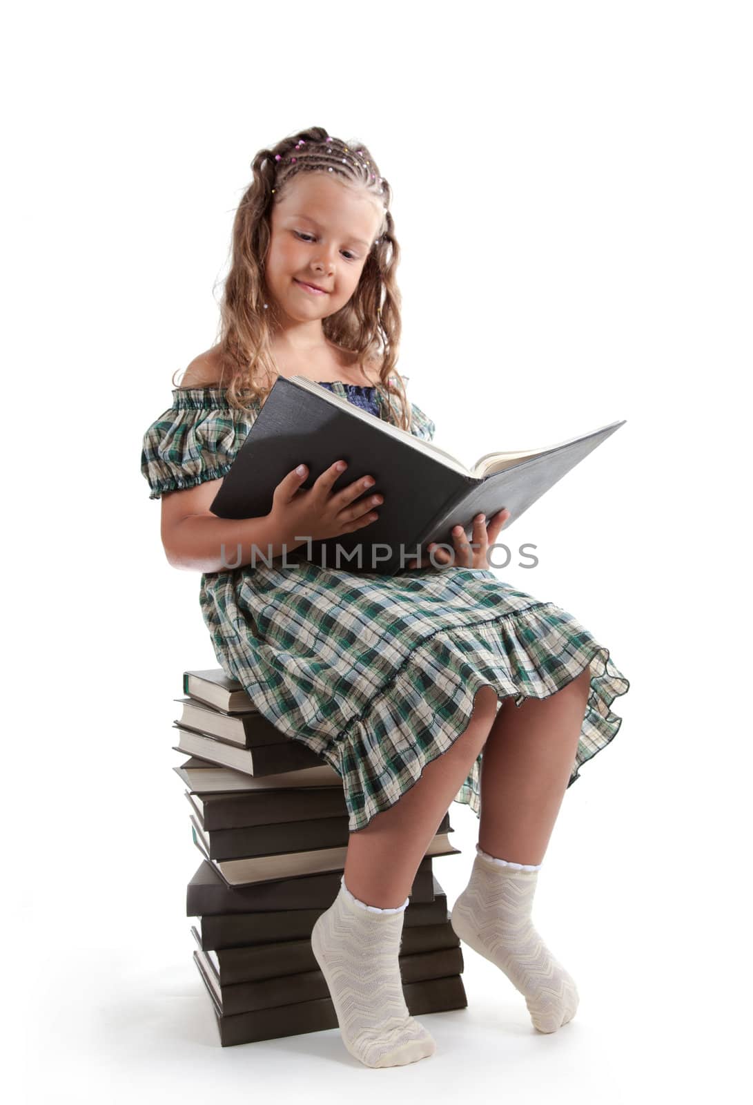 Little girl with pigtails reading a book, isolated on white background 