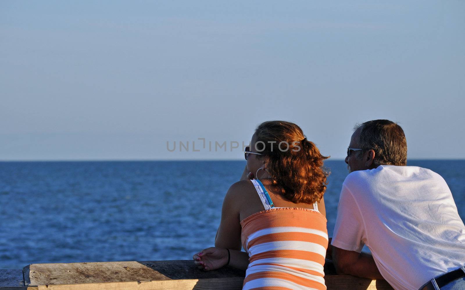 Couple stares out at the ocean by RefocusPhoto