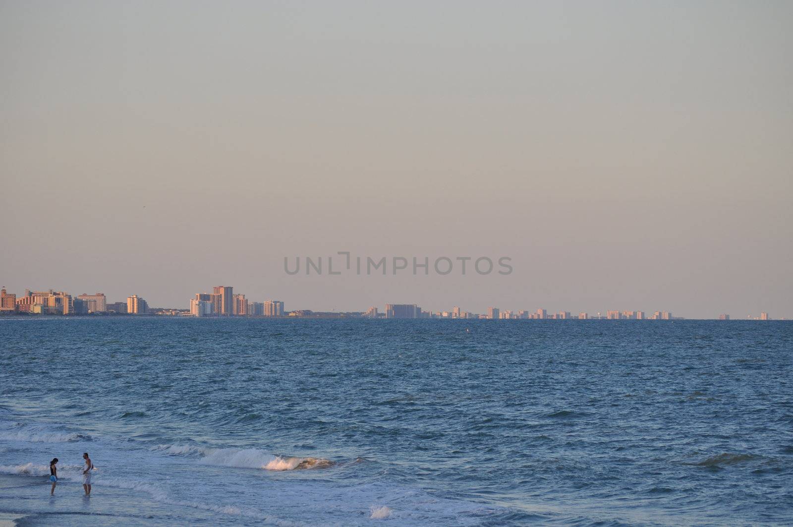 Couple talks in the waves on the Myrtle Beach Coastline by RefocusPhoto