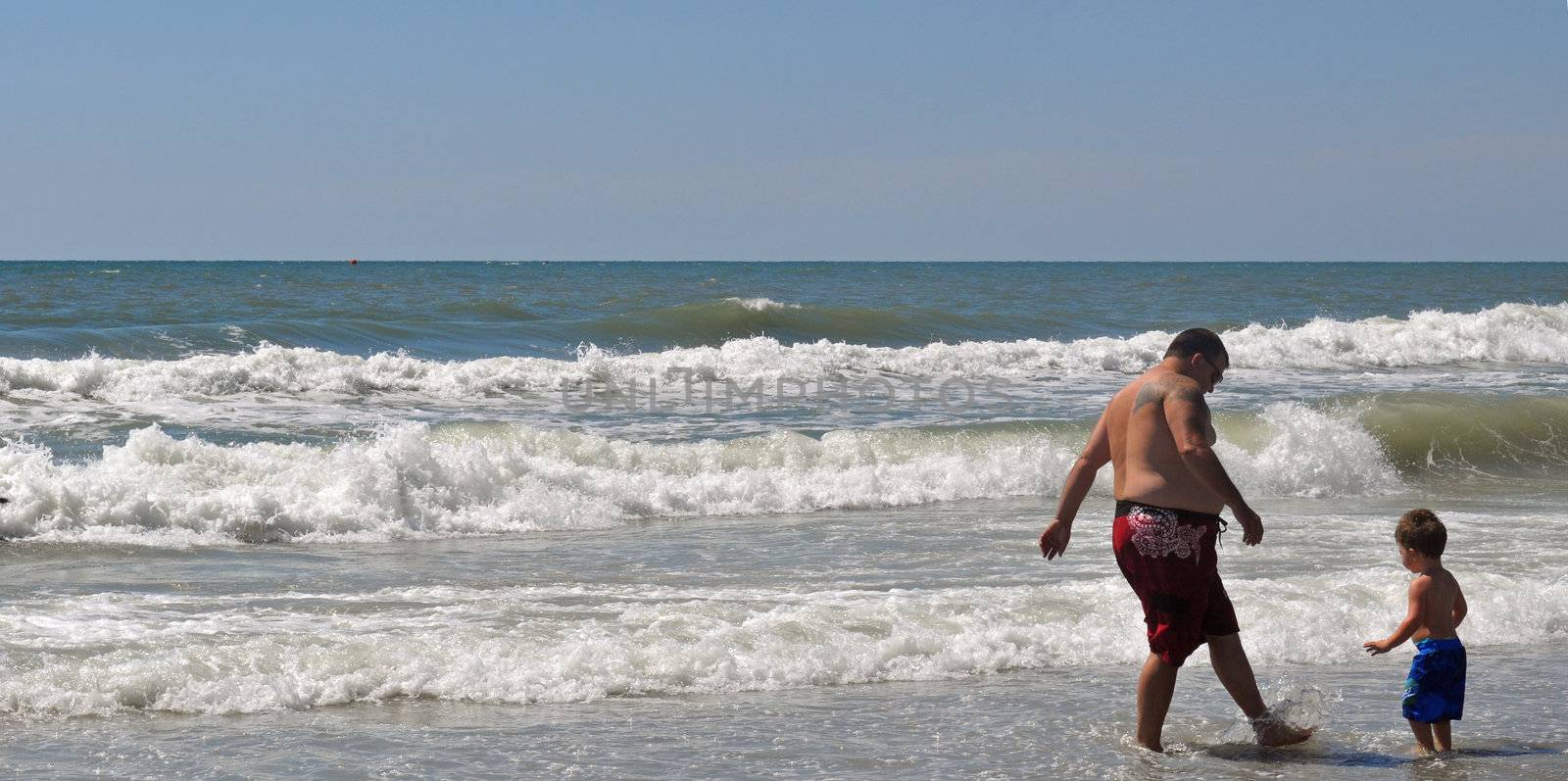 Father and Son Splash in the ocean by RefocusPhoto