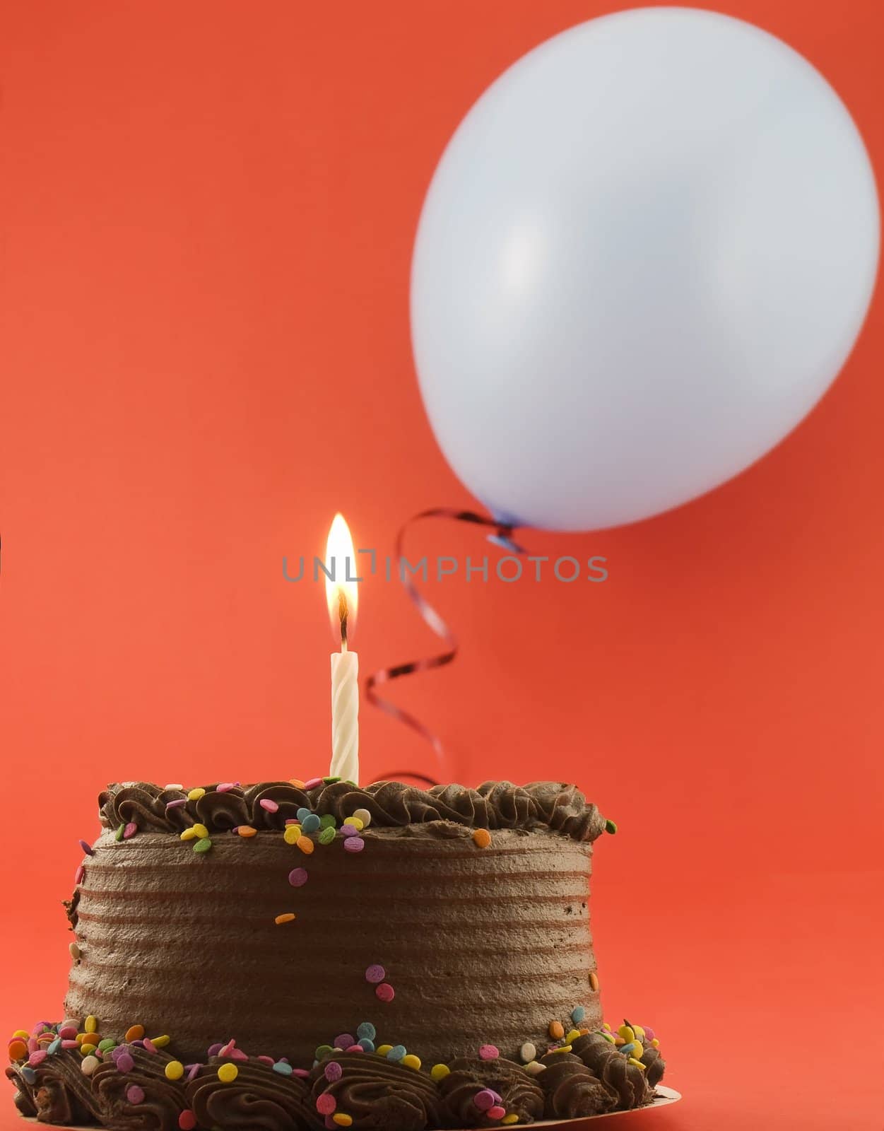 Chocolate cake with candle and balloon in the background