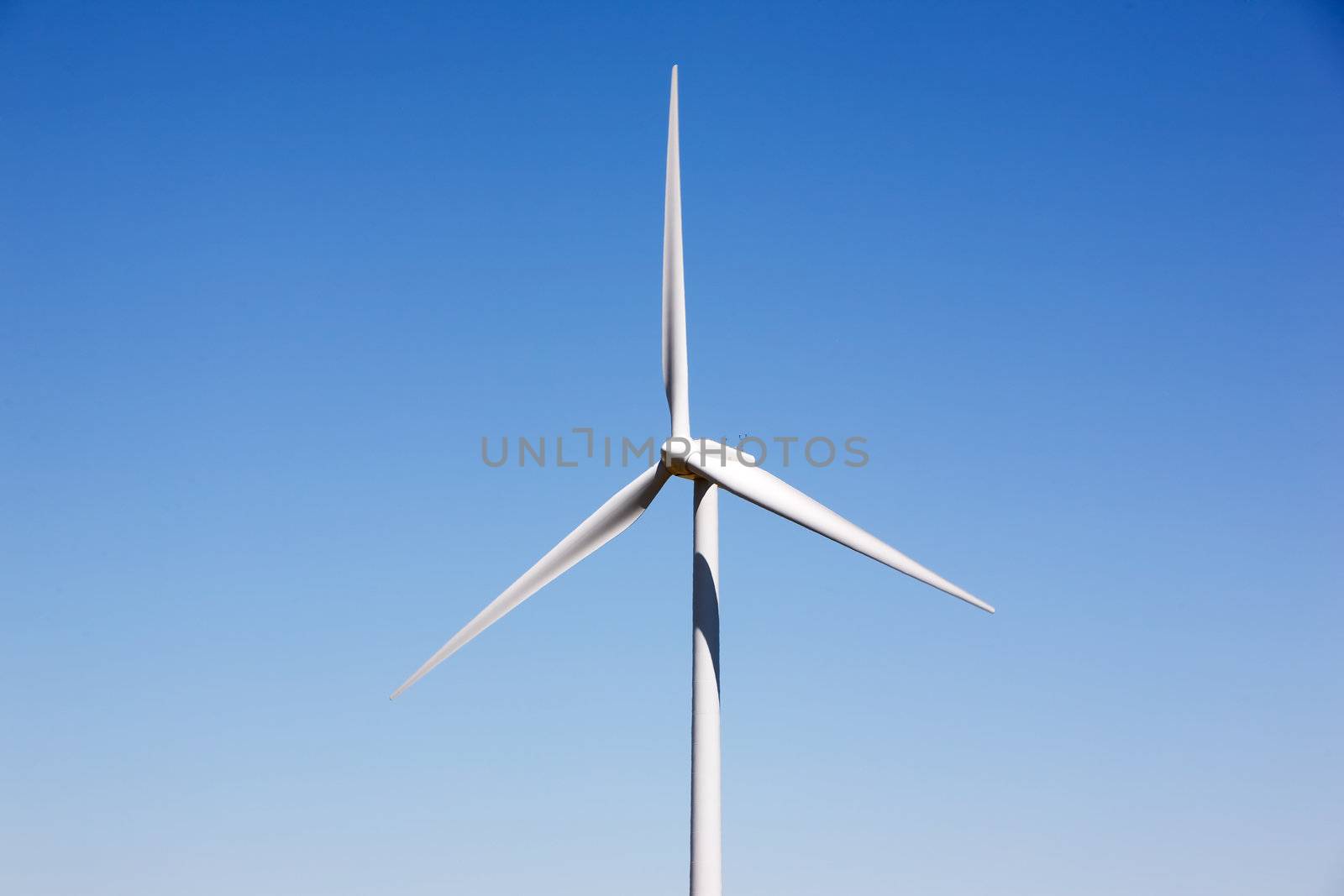 A detail of a wind turbine against a deep blue sky