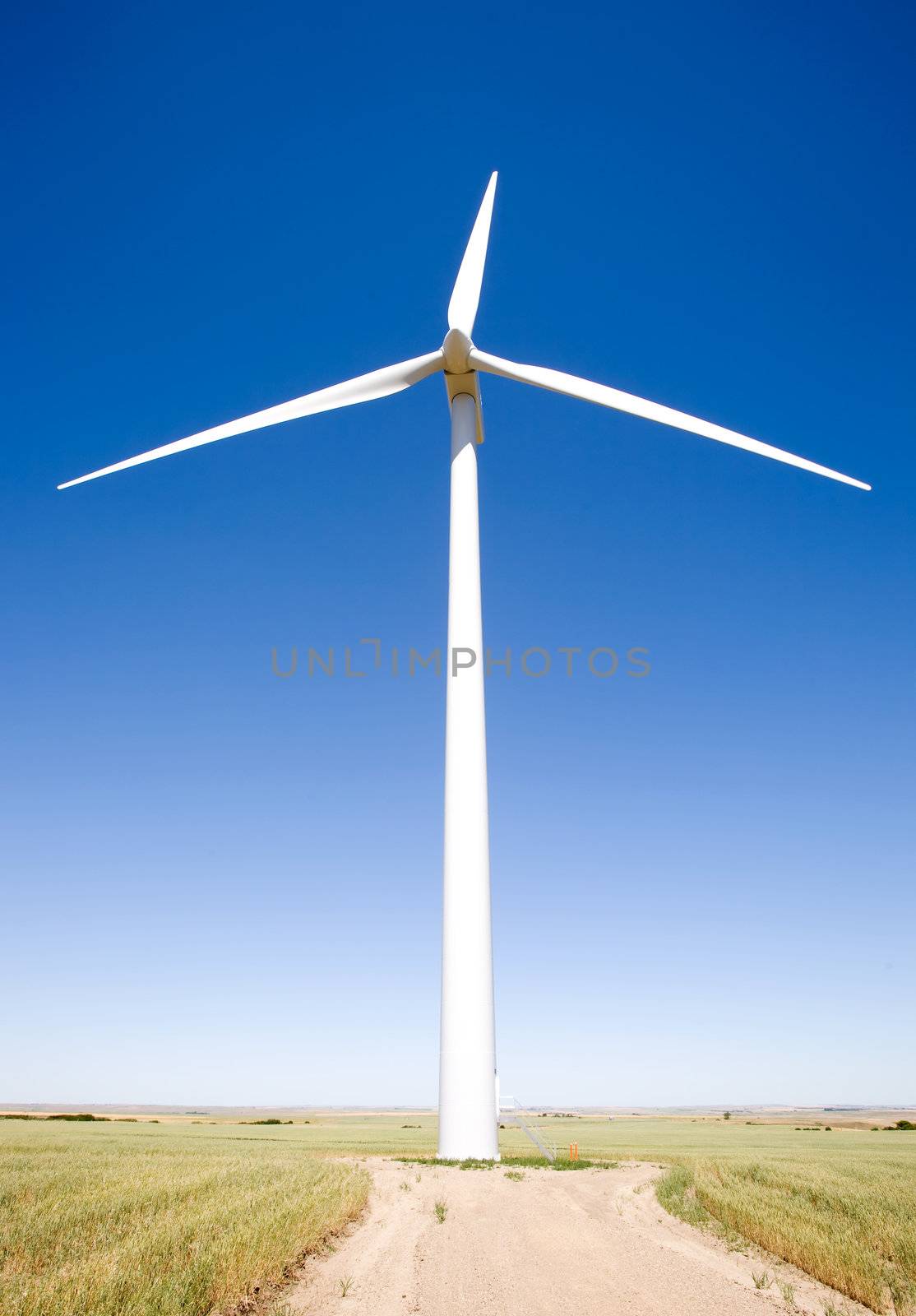 A wind turbine on the flat prairie viewed from below