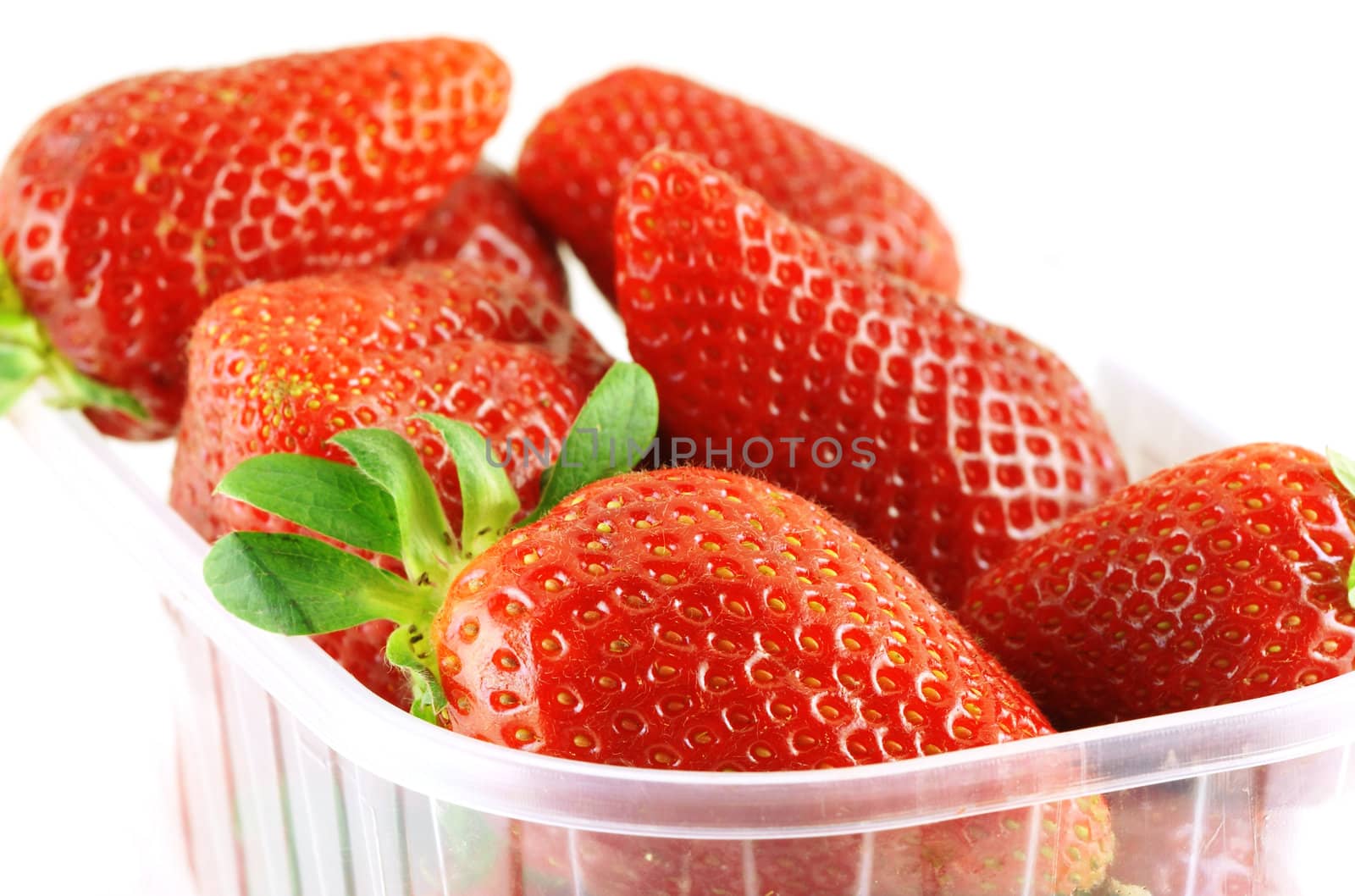 close up of a container full of fresh strawberry over white