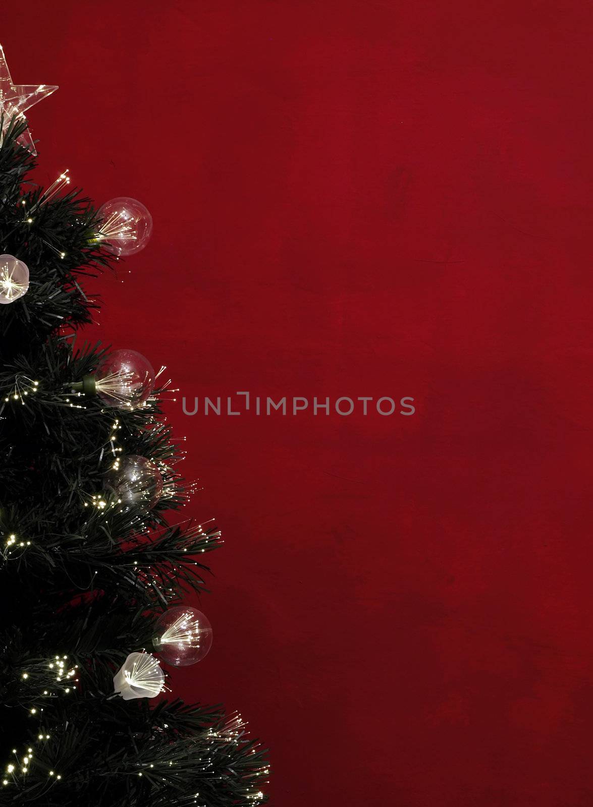 Details of a fibre-optic decorated Christmas Tree against a red wall