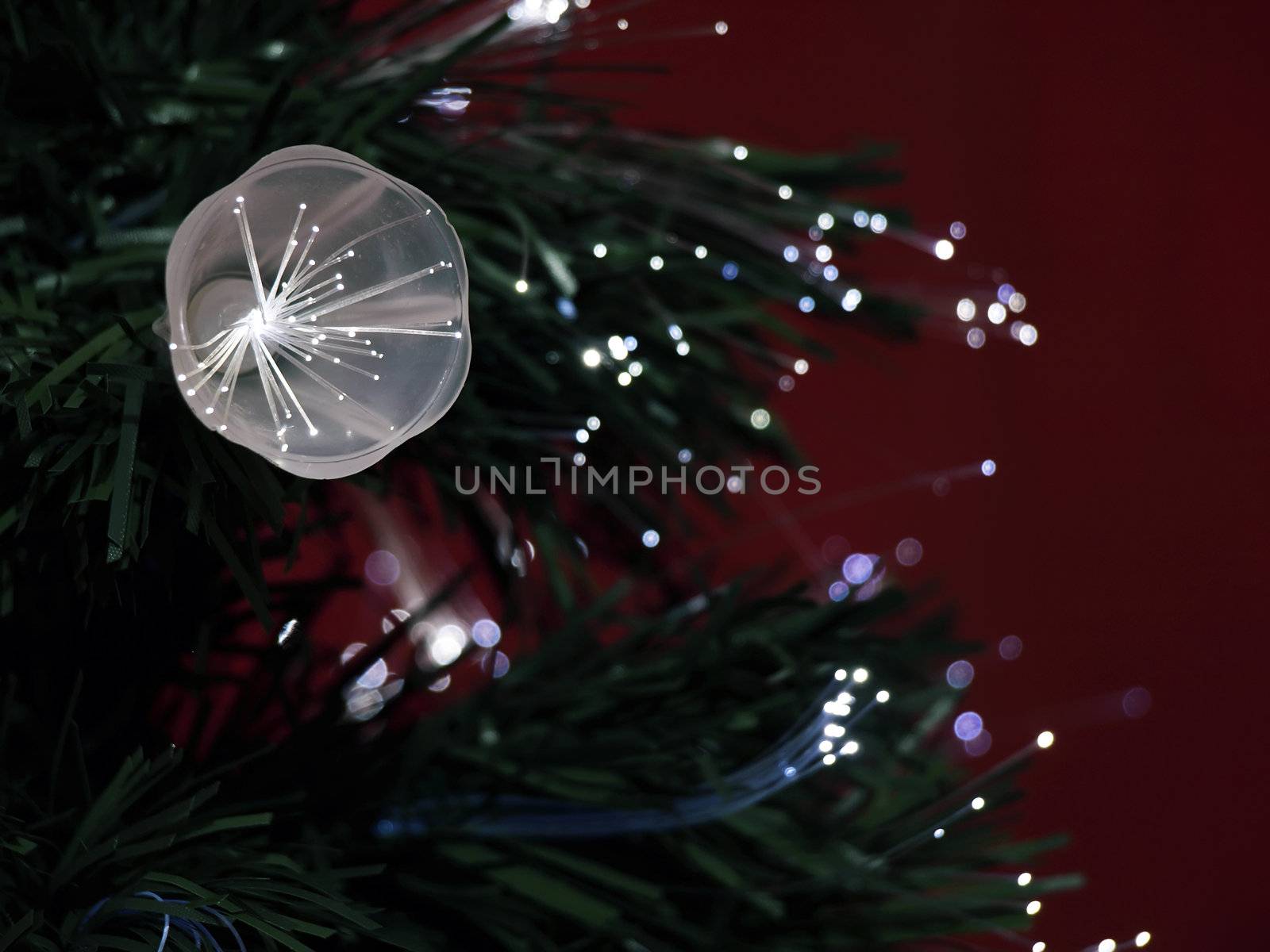 Details of a fibre-optic decorated Christmas Tree against a red wall