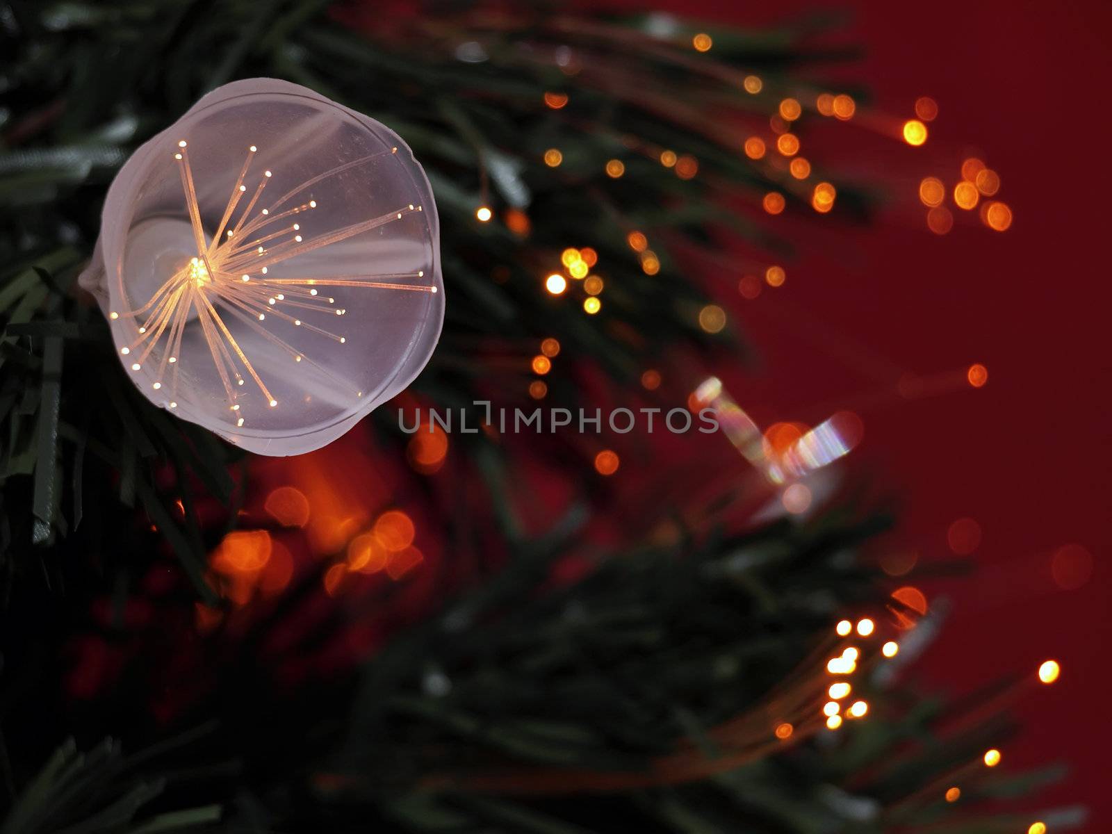 Details of a fibre-optic decorated Christmas Tree against a red wall