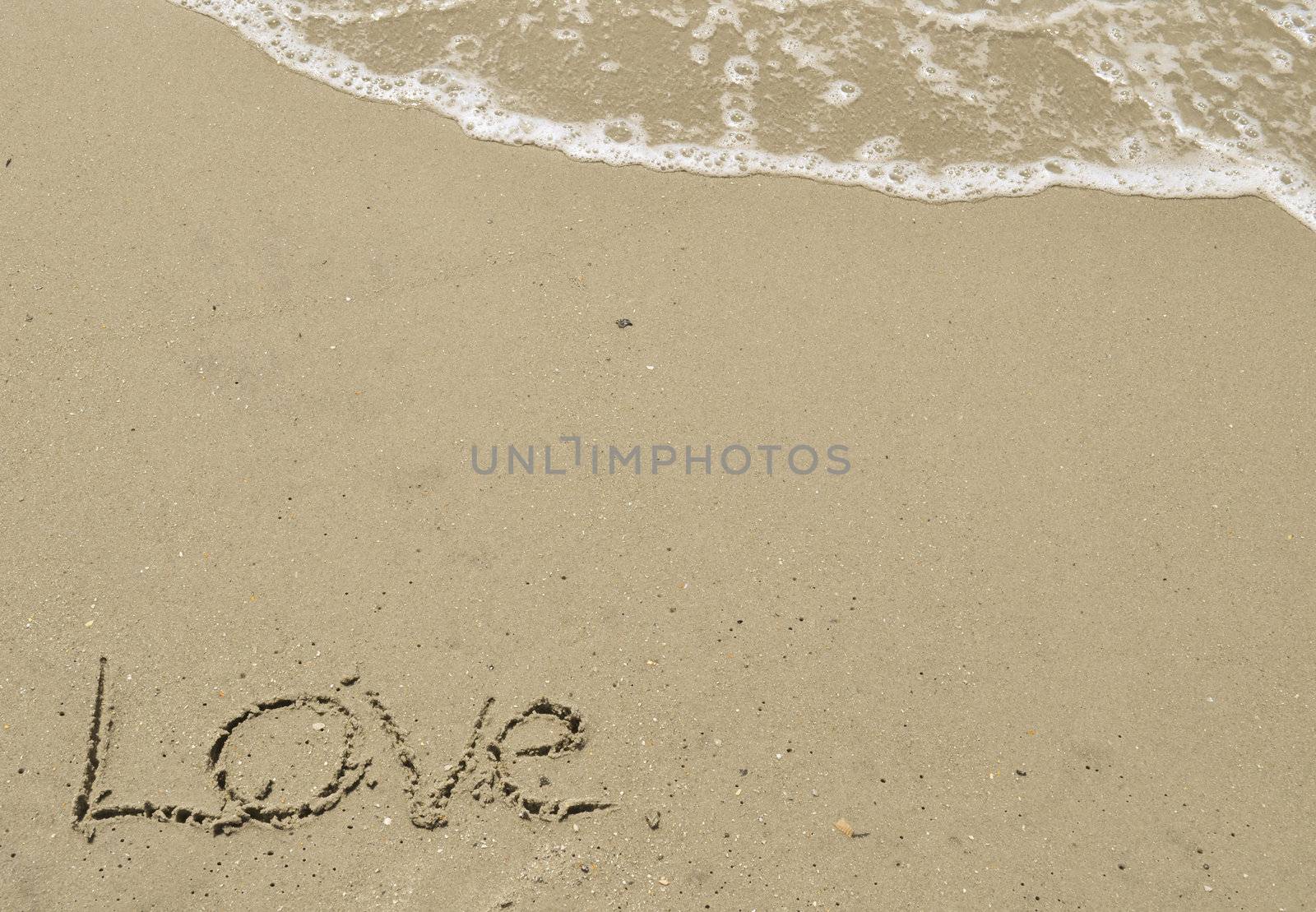 Love written in the sand with wave by RefocusPhoto