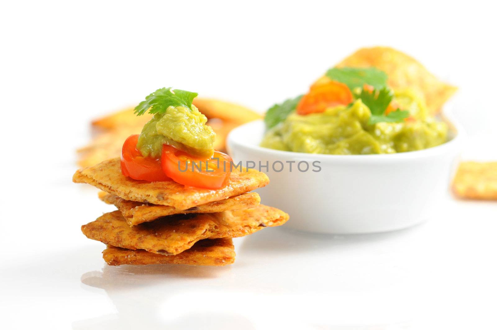 Crackers topped with fresh guacamole and cilantro.