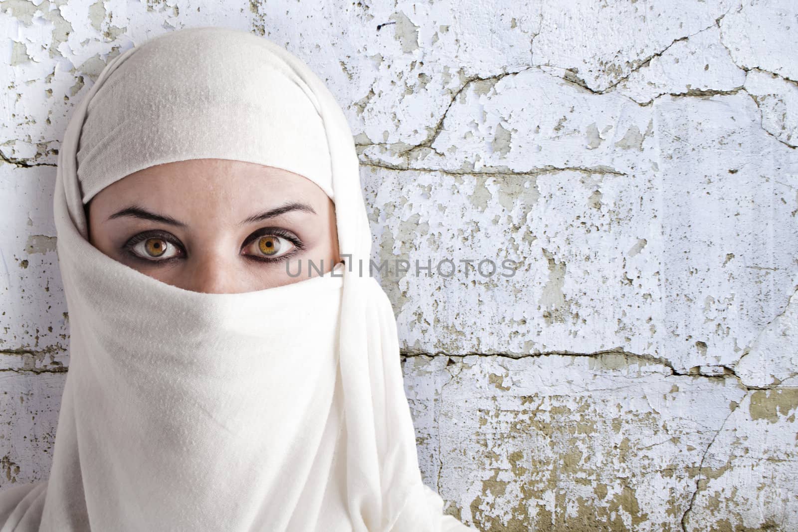 woman dressed in Arab costume, rusty wall in the background