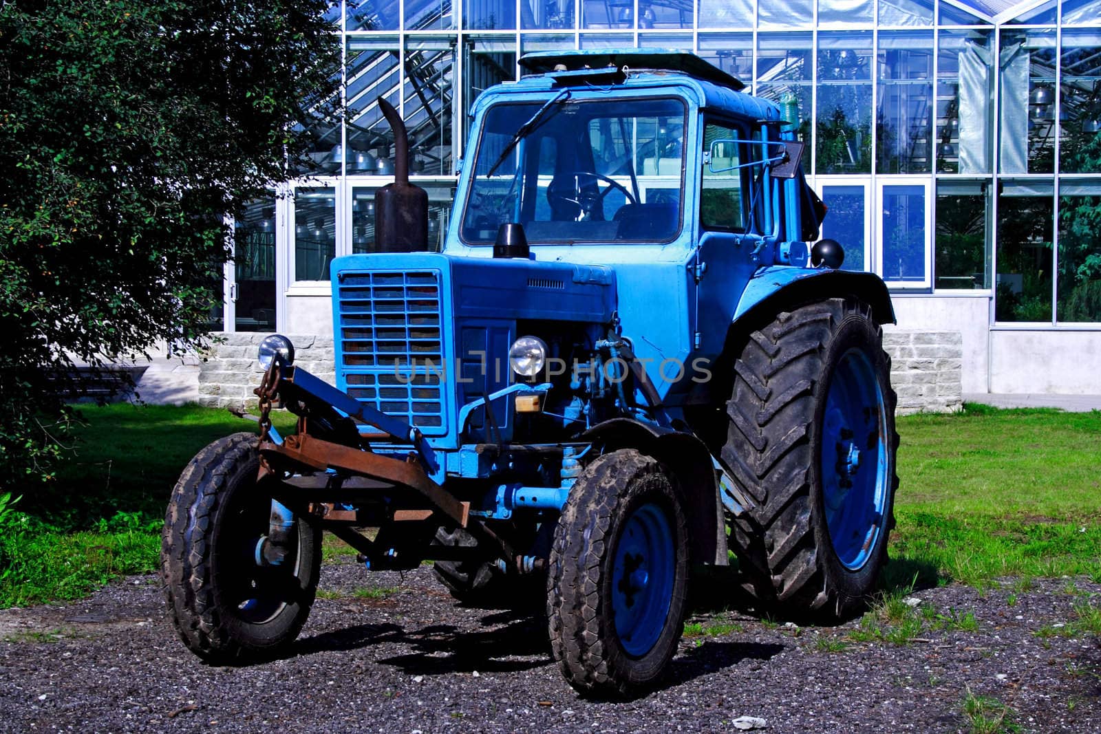 Painted in blue tractor standing before glass building