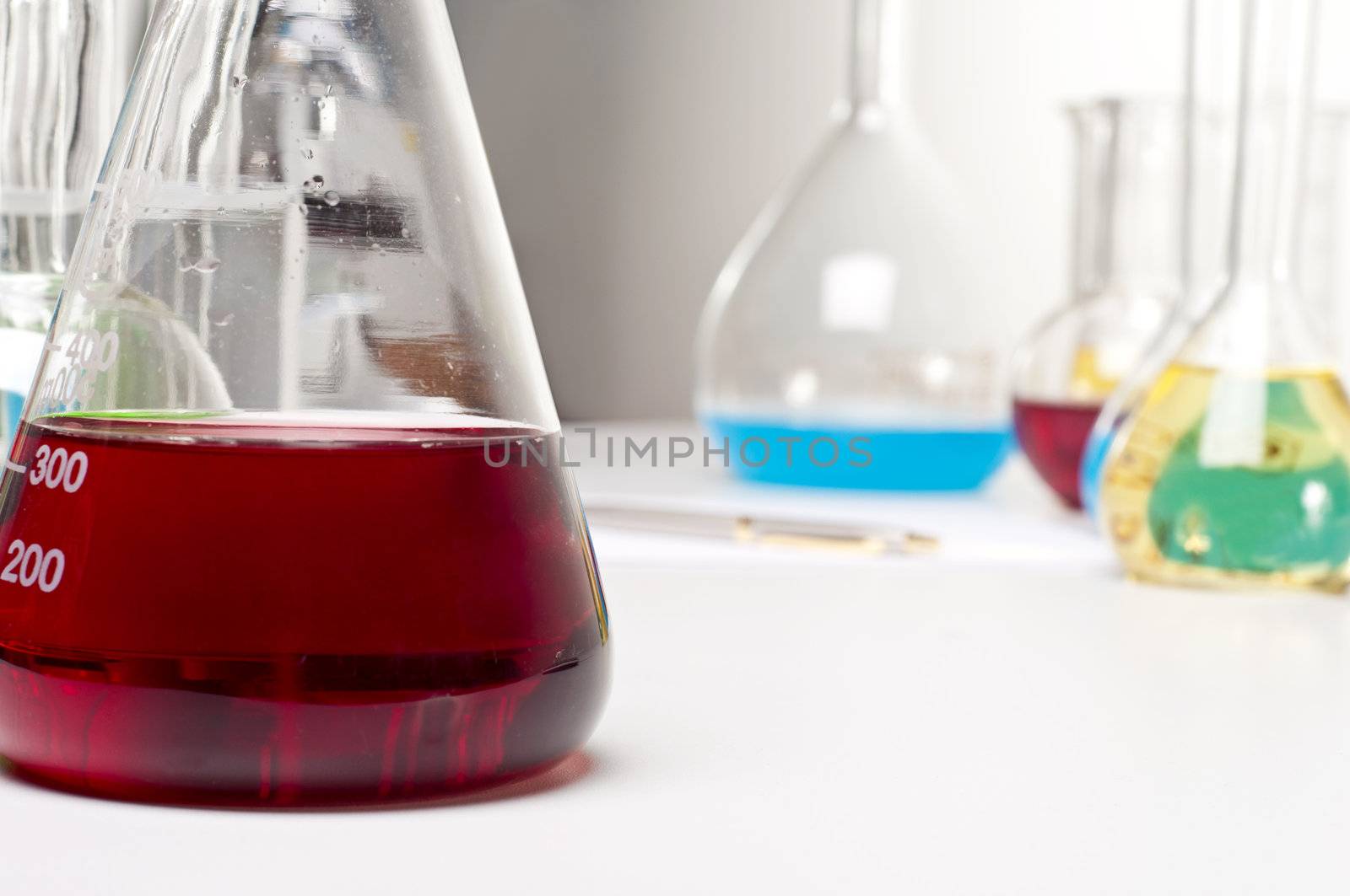 flask with red liquid, in the background laboratory items