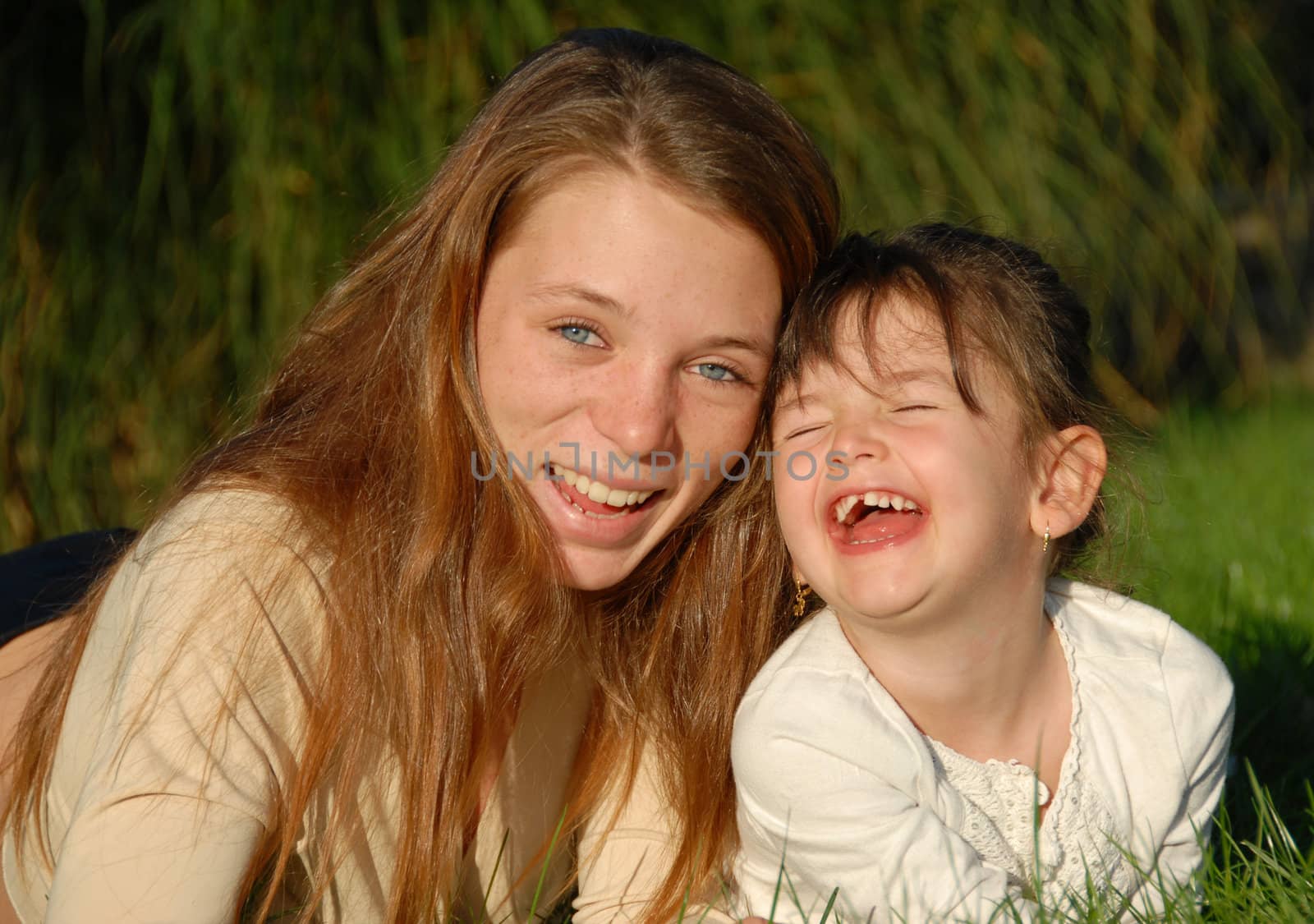 two smiling sisters: teenager and little girl

