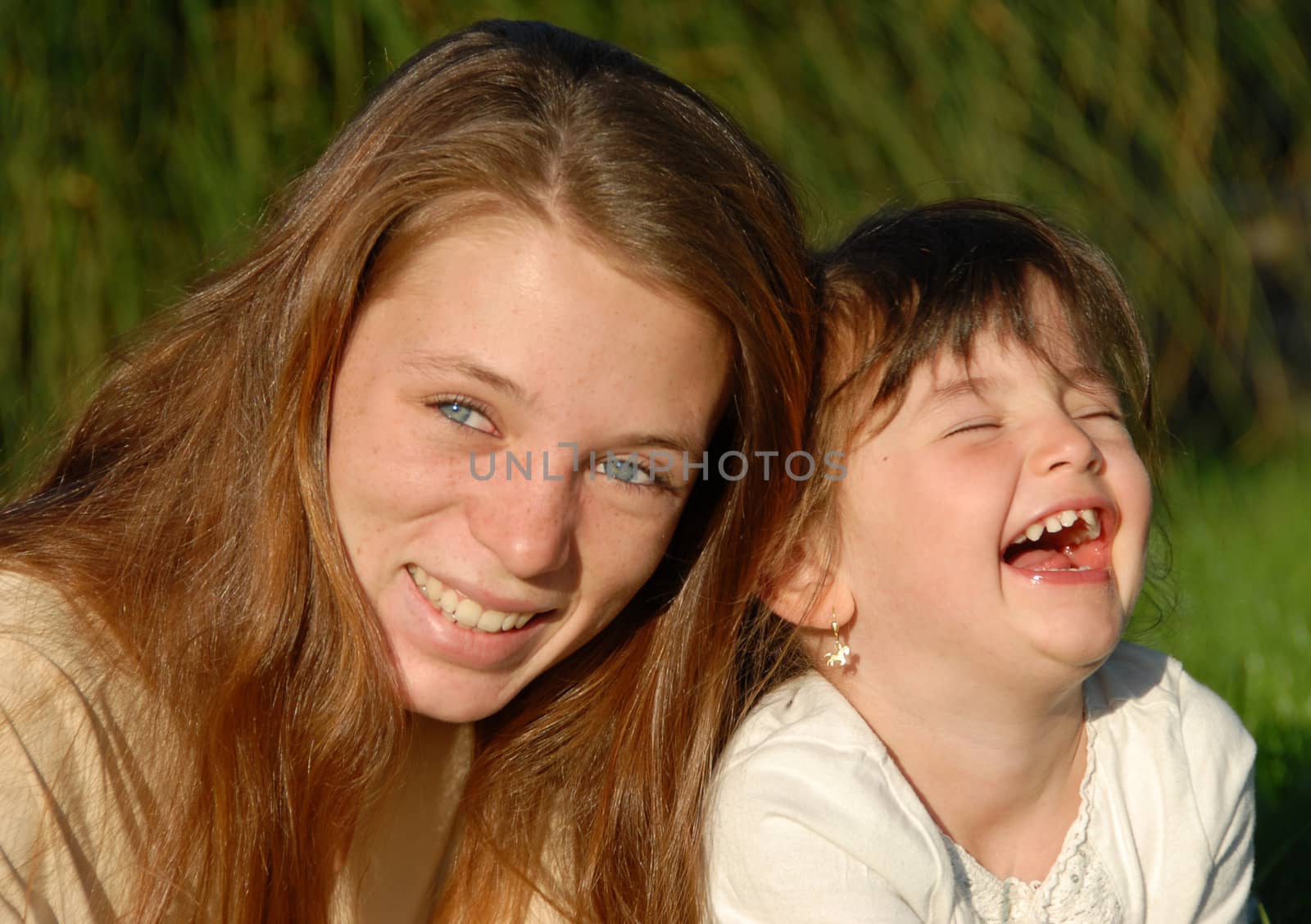 two smiling sisters: teenager and little girl

