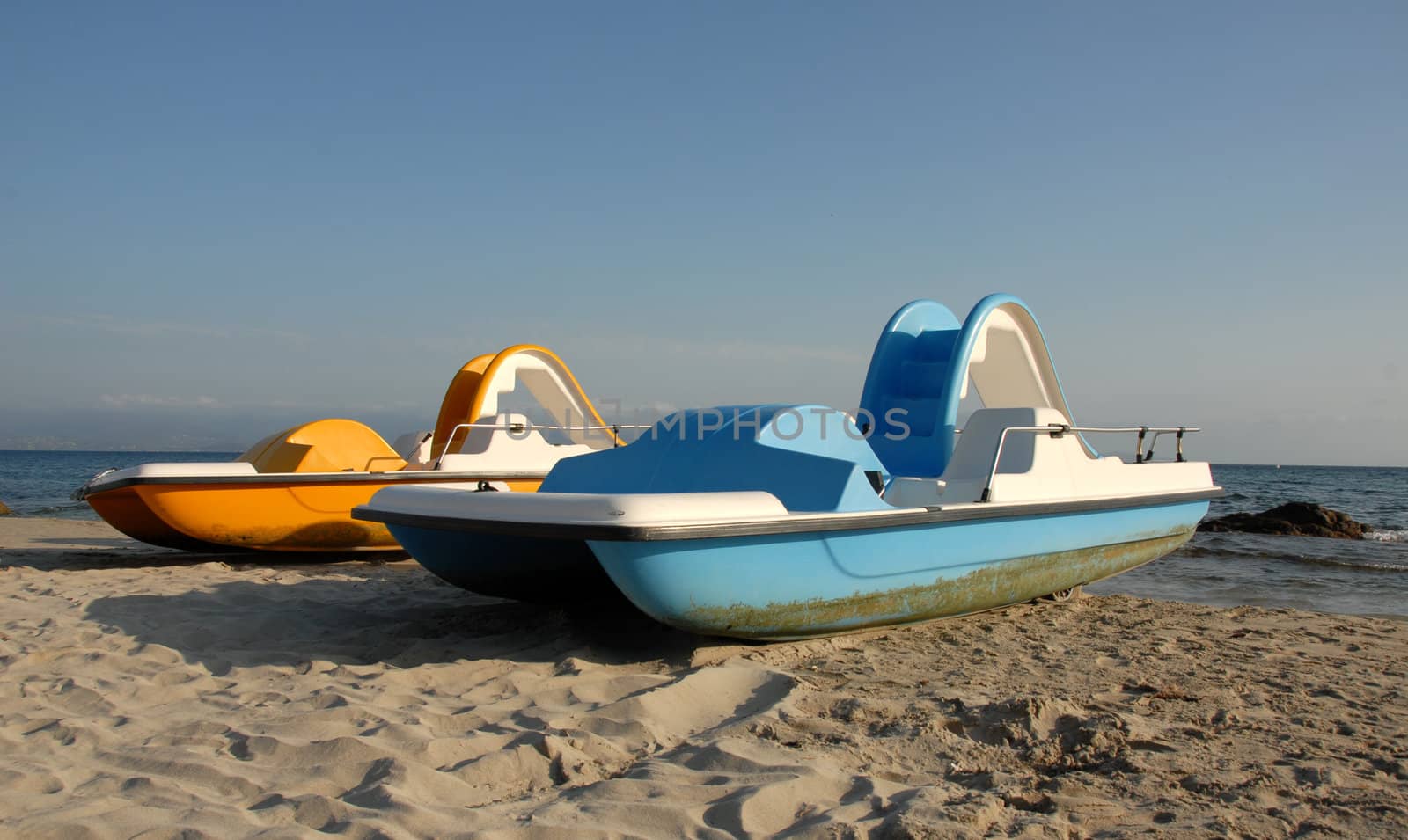 two blue and yellow pedallos on a beach of corse
