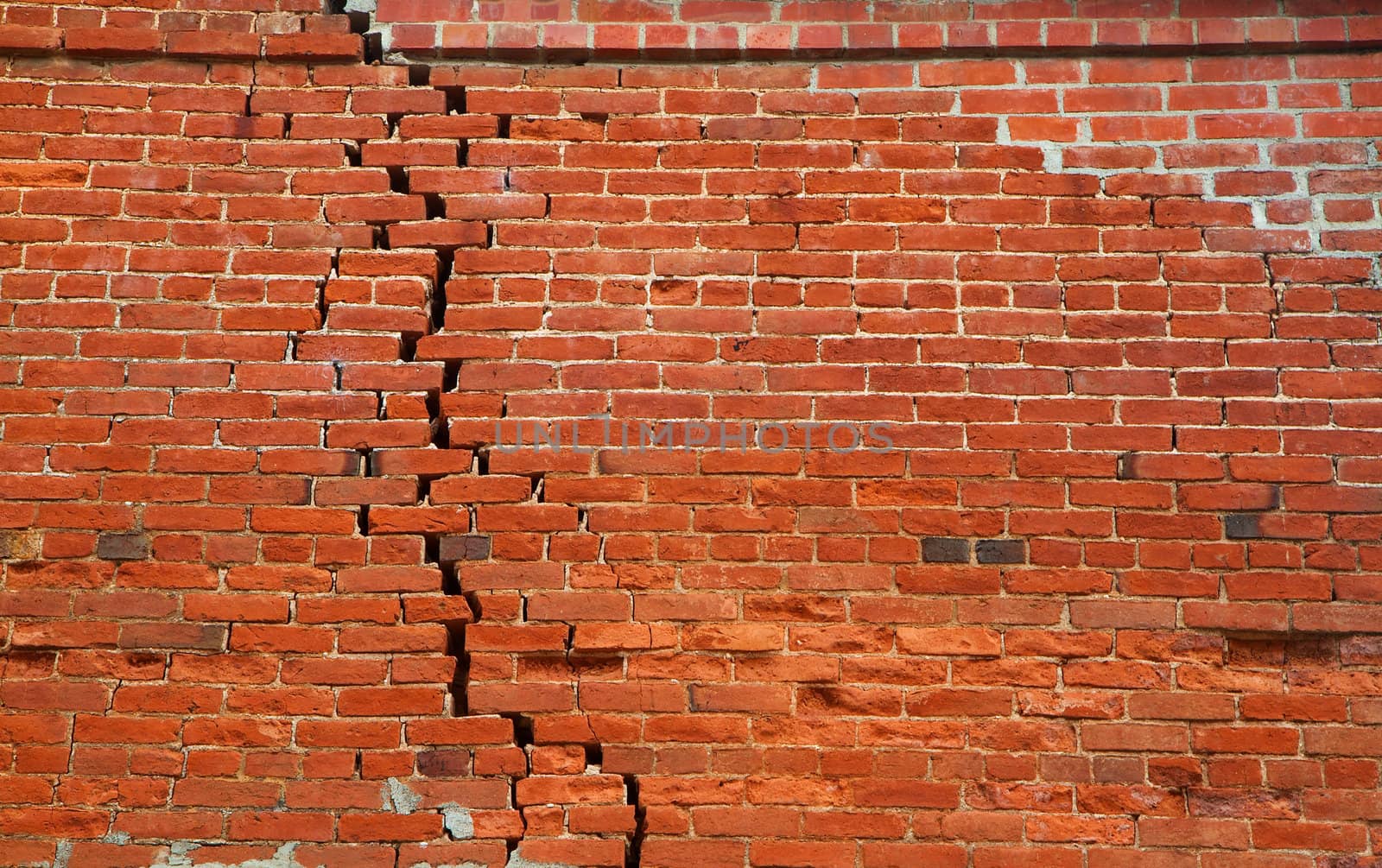 Large crack of separating bricks in a red wall