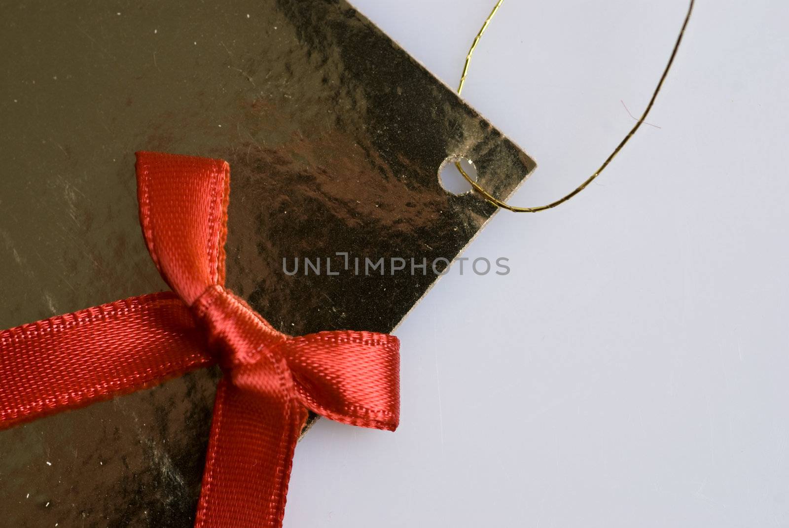 red ribbon tied in a bow on gold gift bag