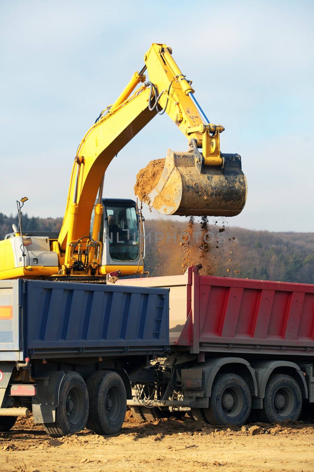 Yellow heavy earth mover loading soil in to the lorry