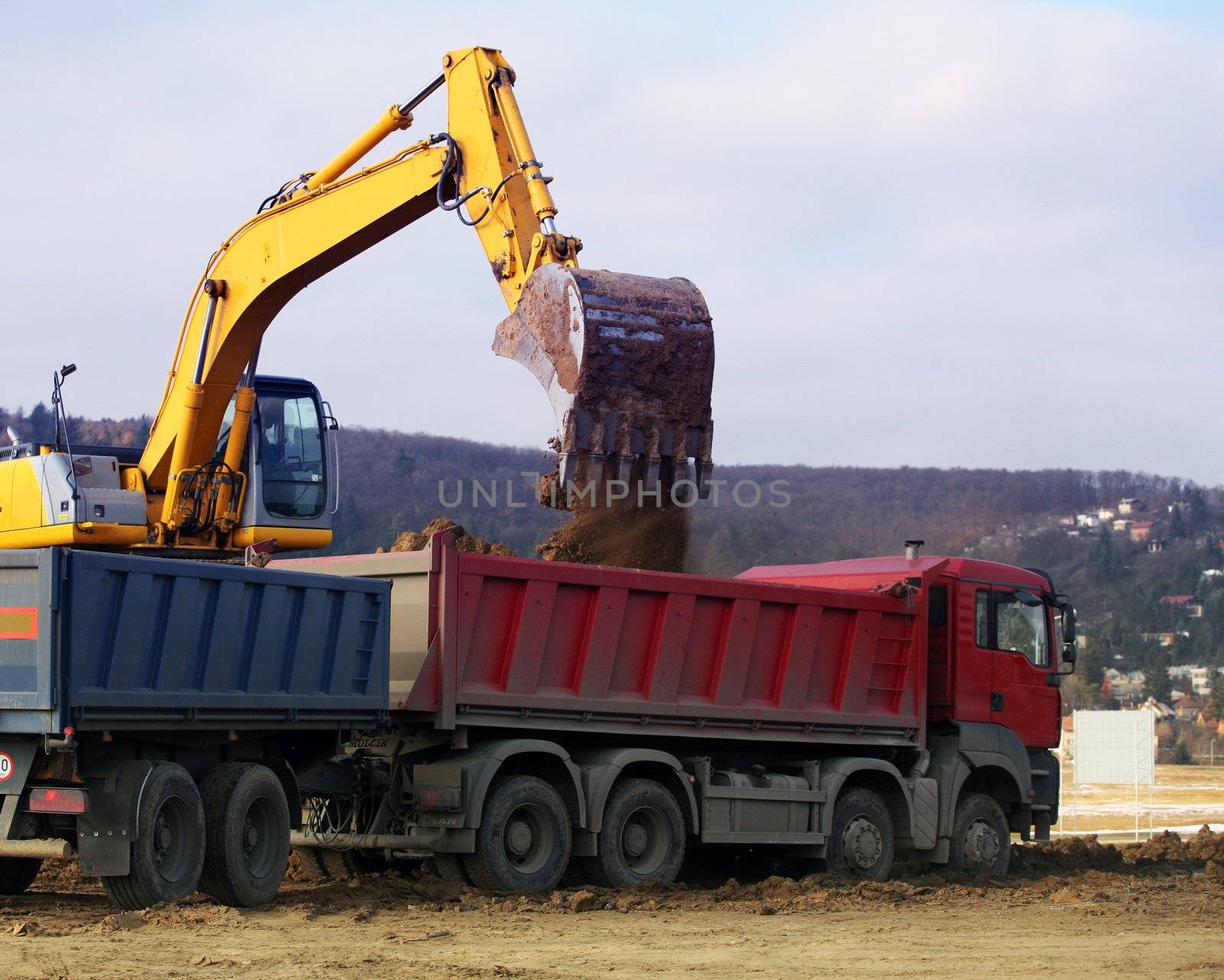 Yellow heavy earth mover loading soil in to the lorry