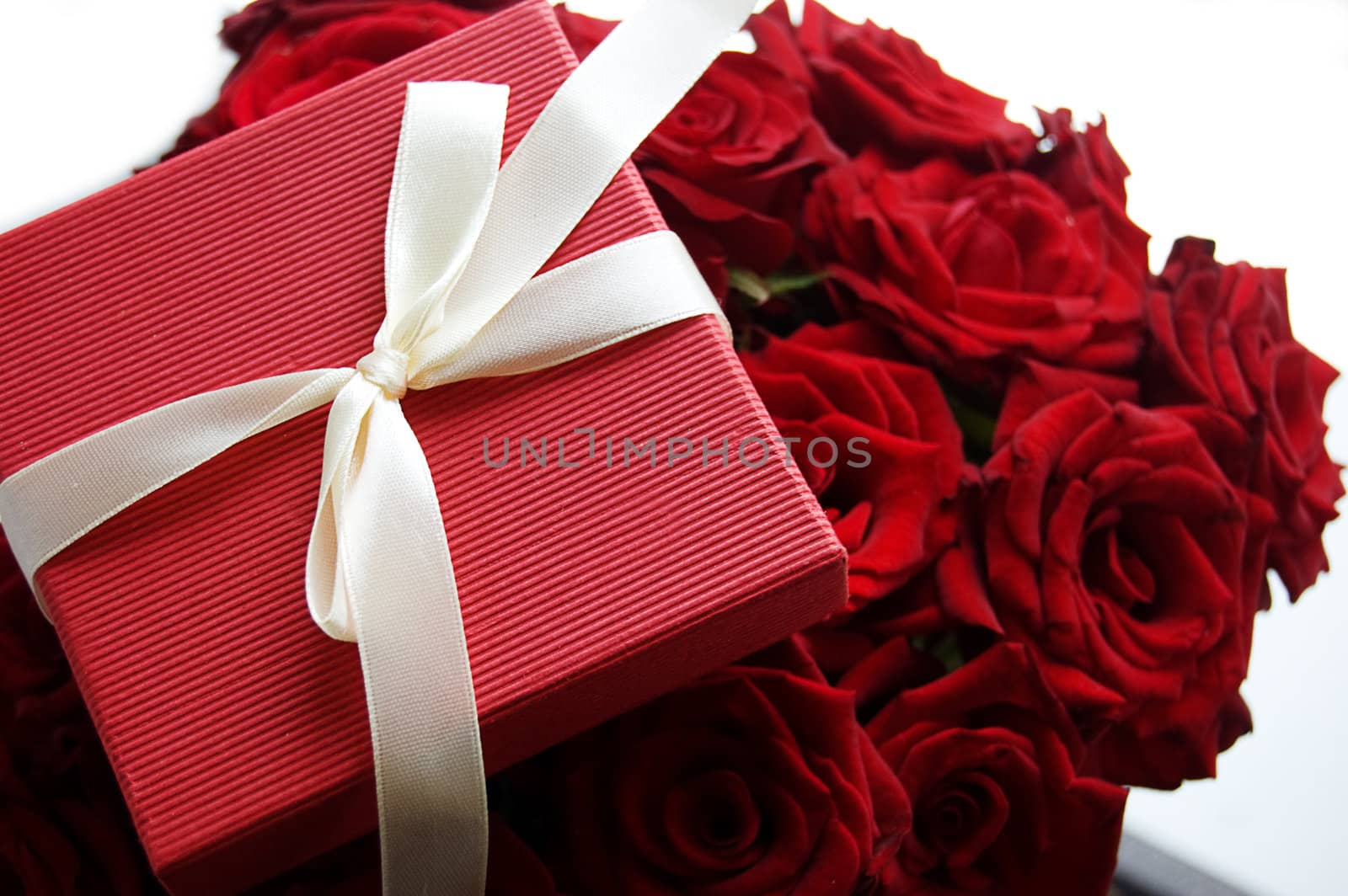 Gift box over red bunch of red roses