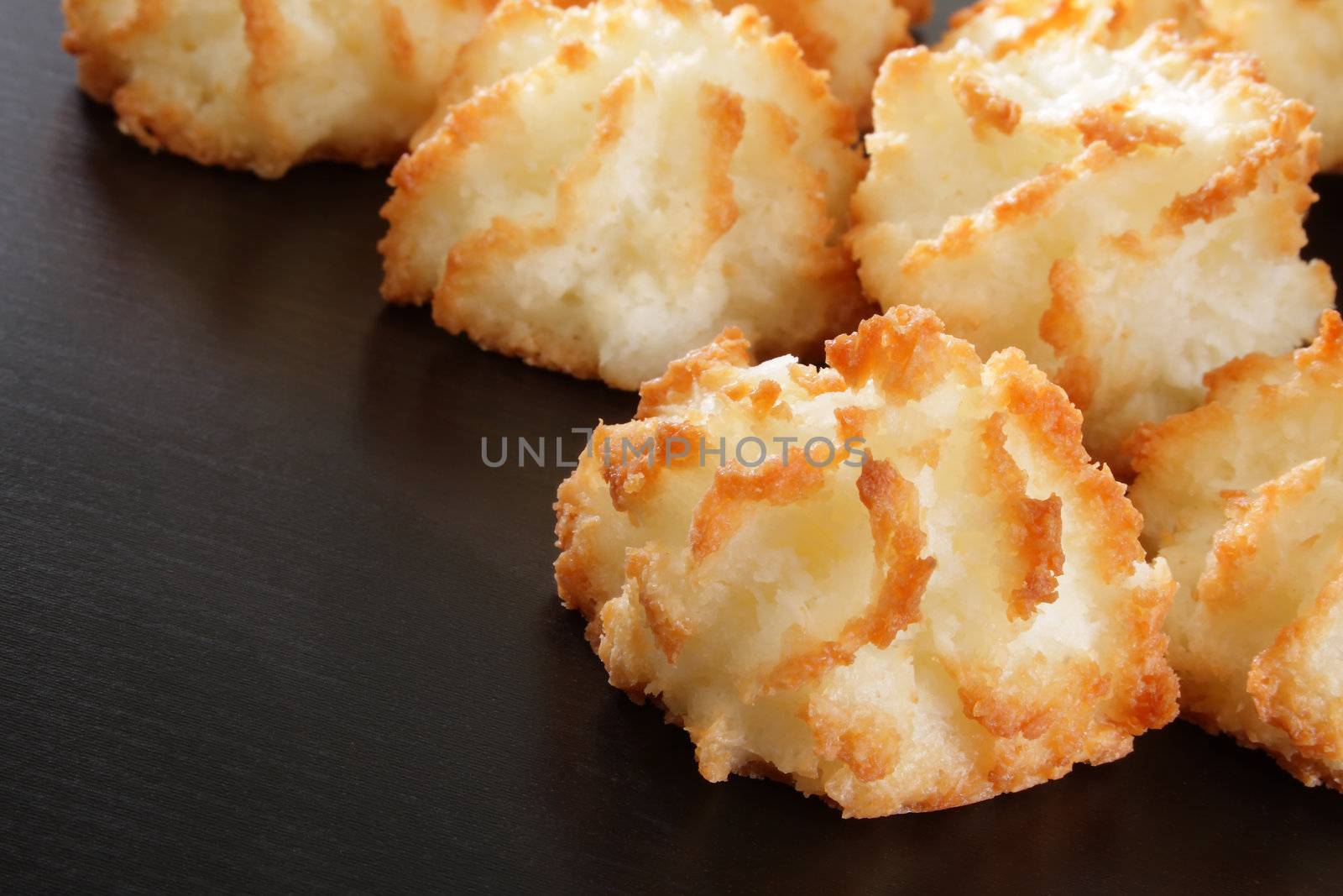 Group of fresh coconut macaroons on dark wood.