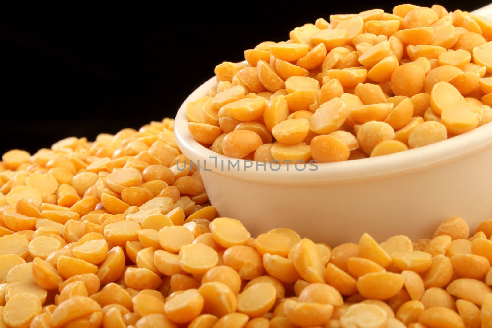 A close up of a measuring cup full of yellow beans.