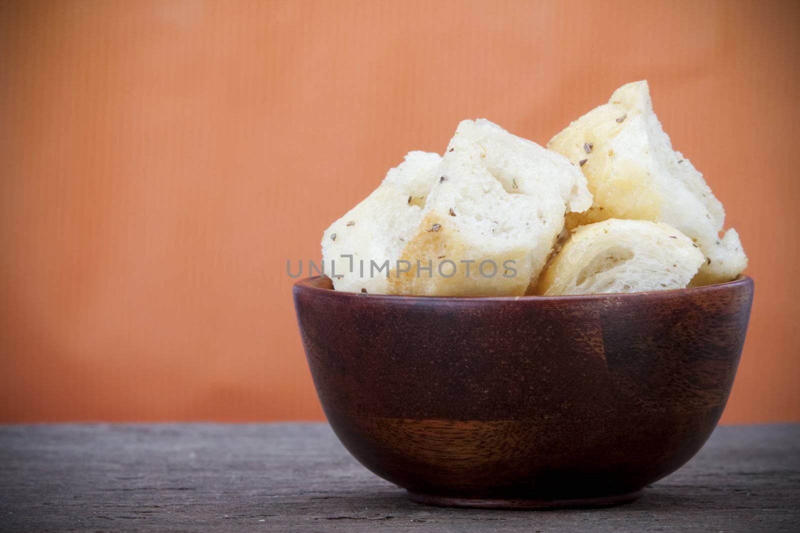 Croutons in a wooden bowl on a slate counter with copy space.