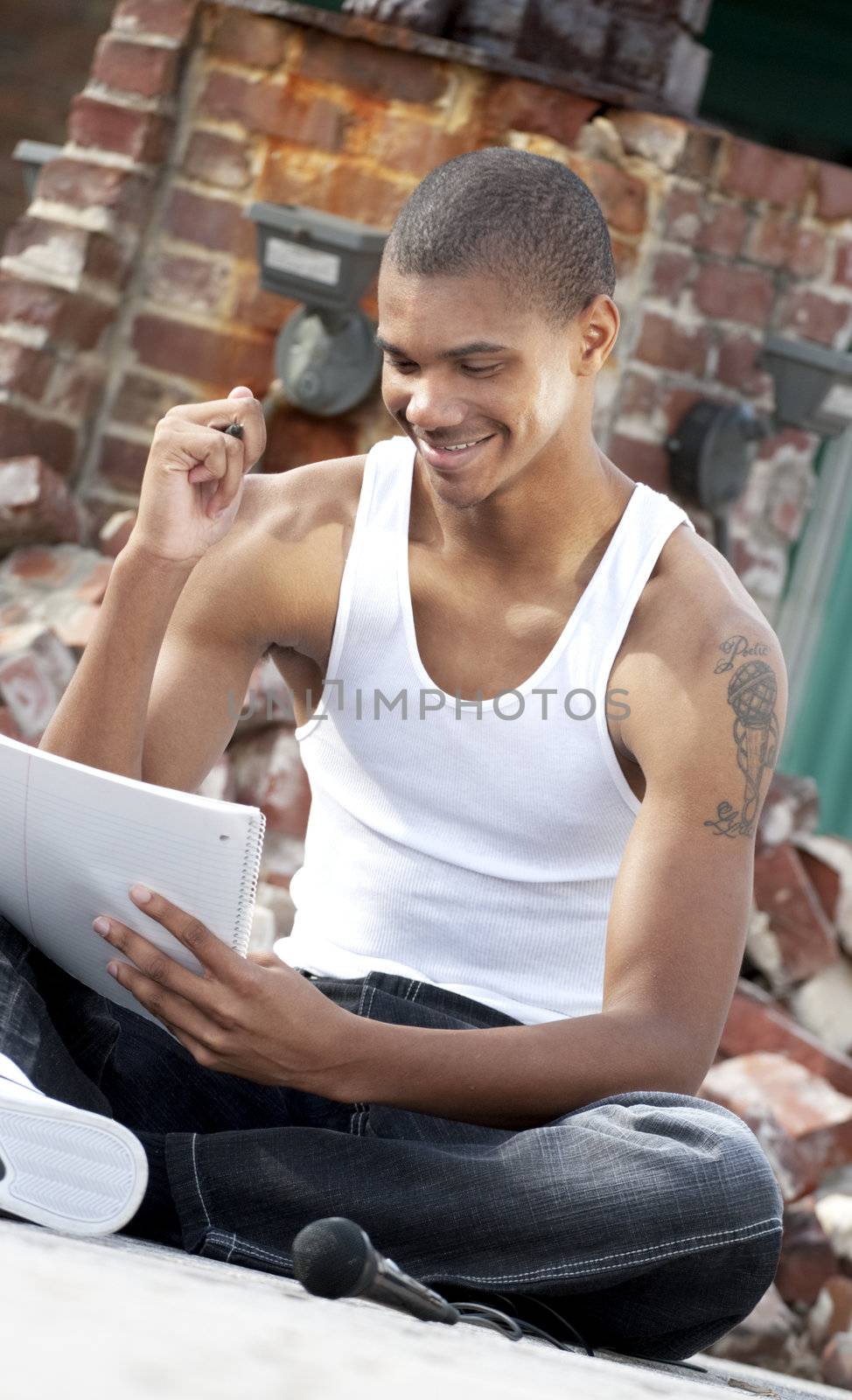 Young African American adult male with a pen and a pad creating poetry.