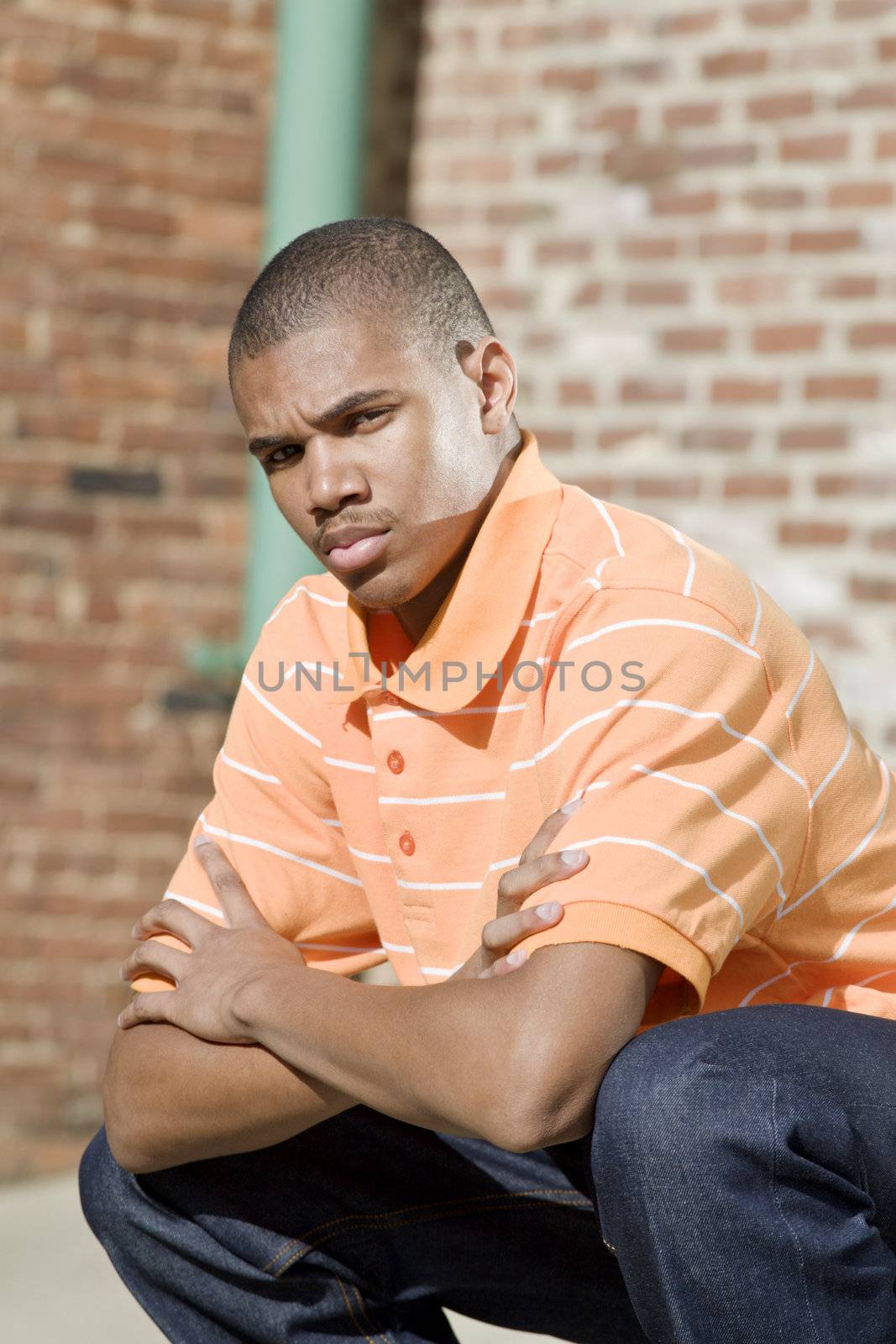 Handsome African American male model posed in front of a brick background.