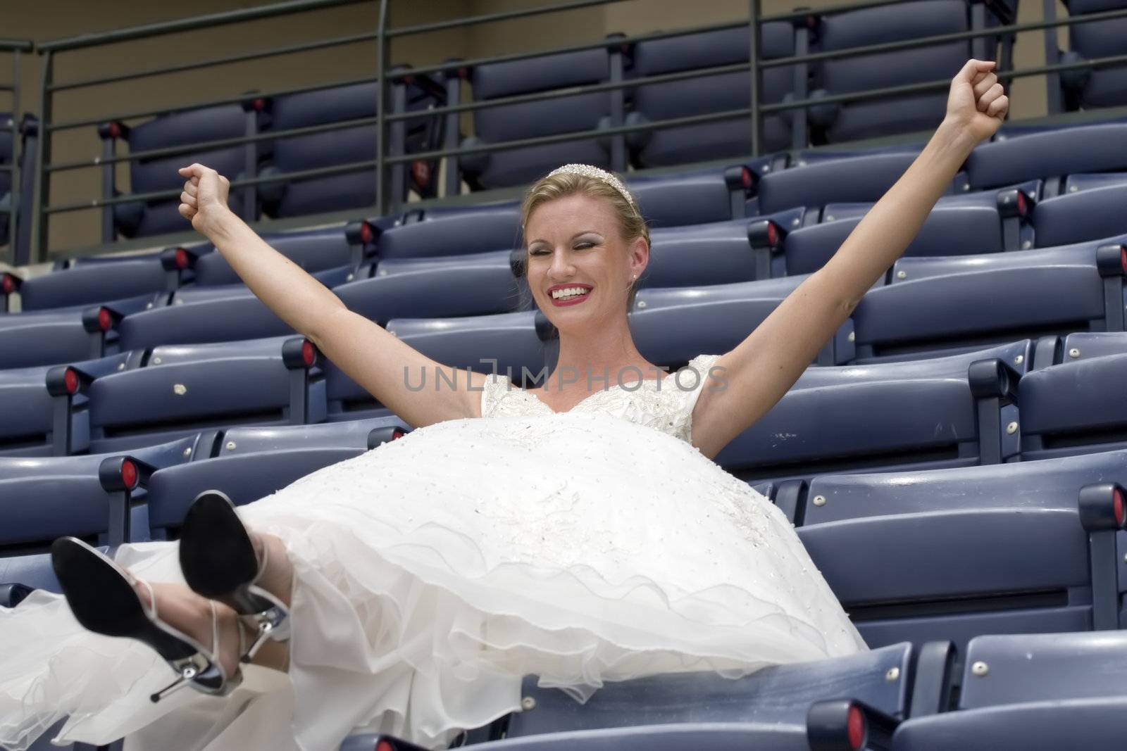 Model wearing wedding gown cheering in a baseball stadium.