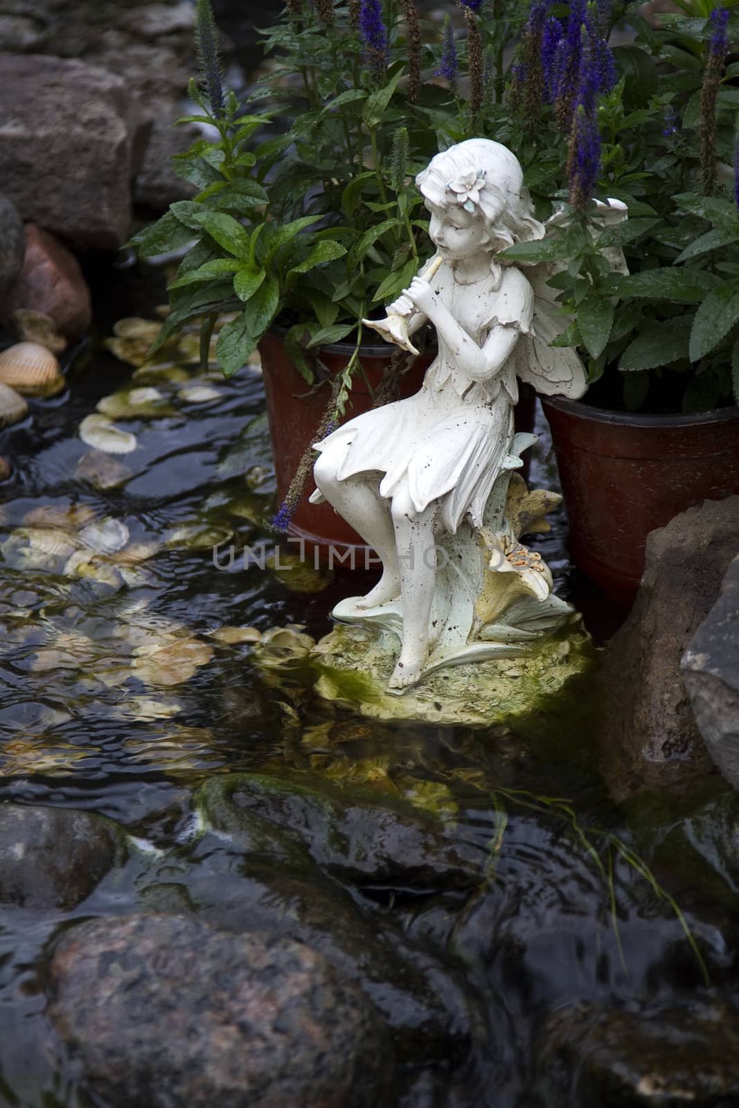 Water nymph statue playing the flute by a stream