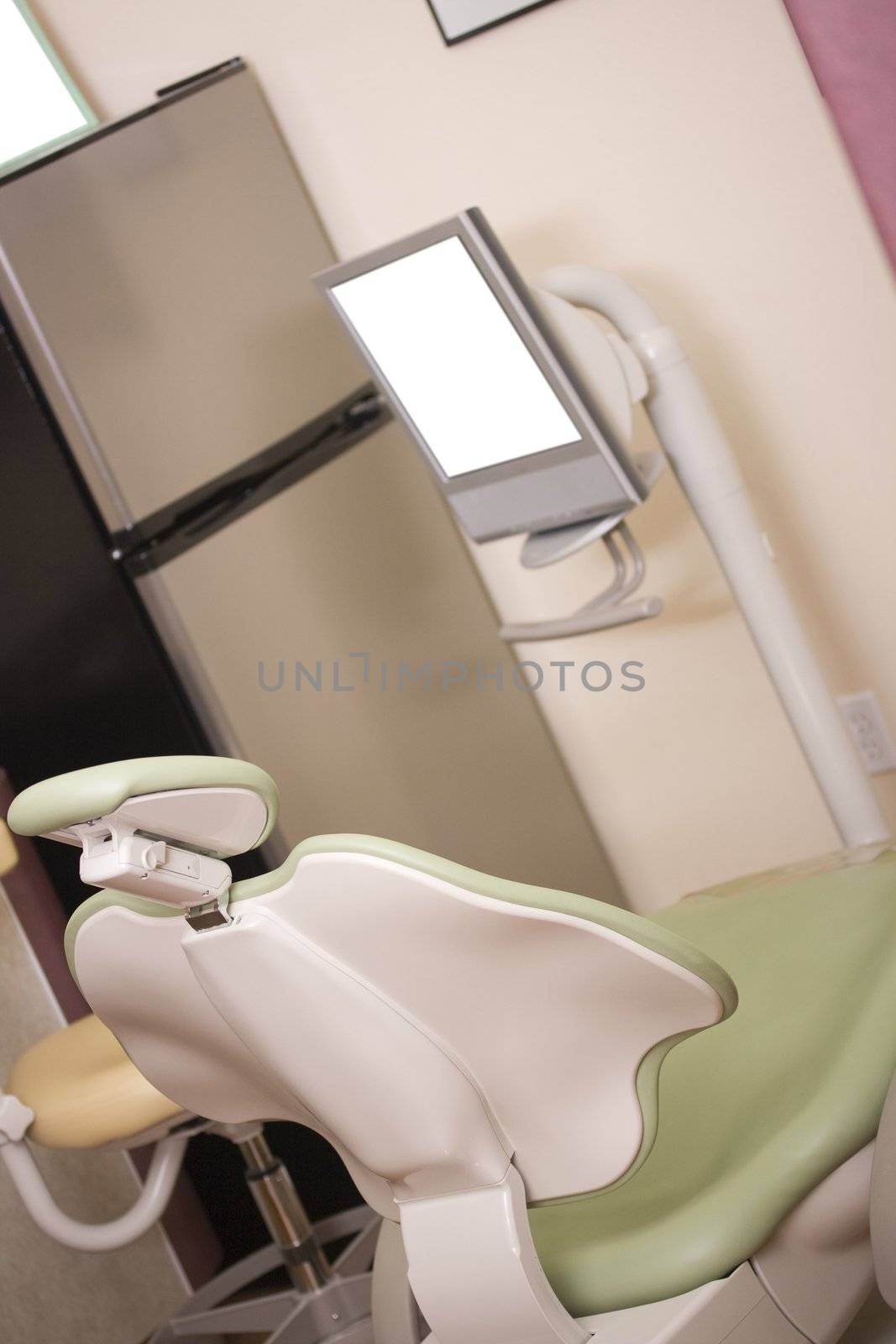 Dentist chair next to a monitor in a dental clinic.