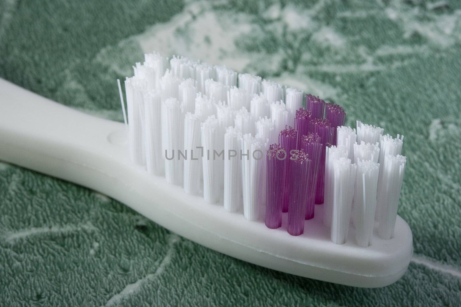White and purple toothbrush on the green countertop.