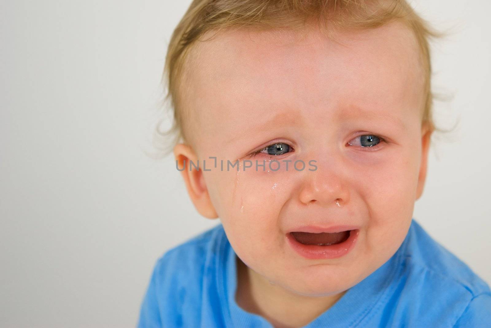 Little red headed boy with blue shirt crying