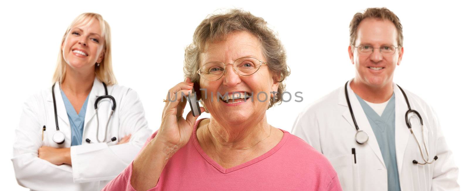 Happy Senior Woman Using Cell Phone with Male and Female Doctors or Nurses Behind Isolated on a White Background.