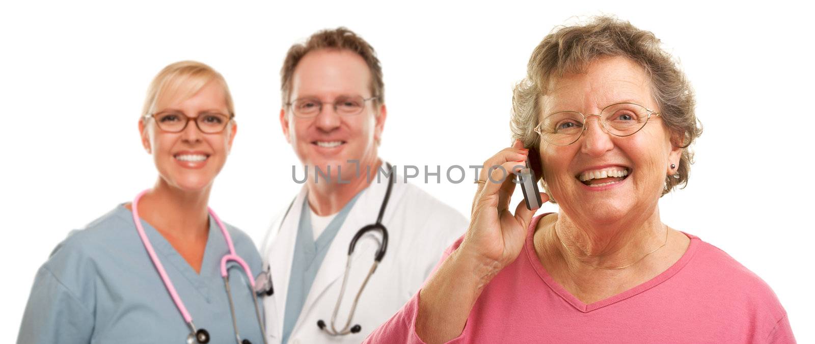 Happy Senior Woman Using Cell Phone and Doctors Behind by Feverpitched